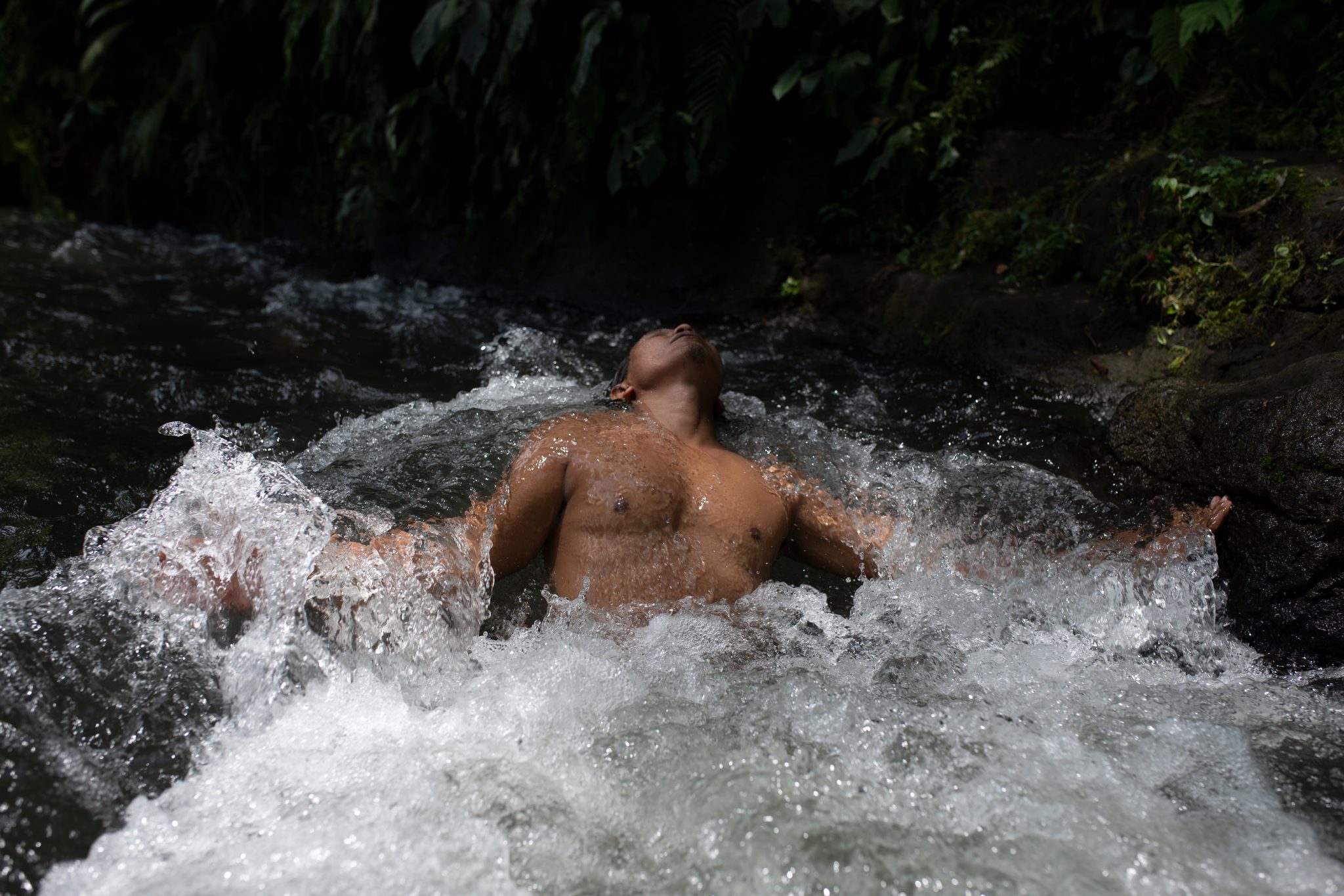 The river pours around him, arms outstretched on the surface.