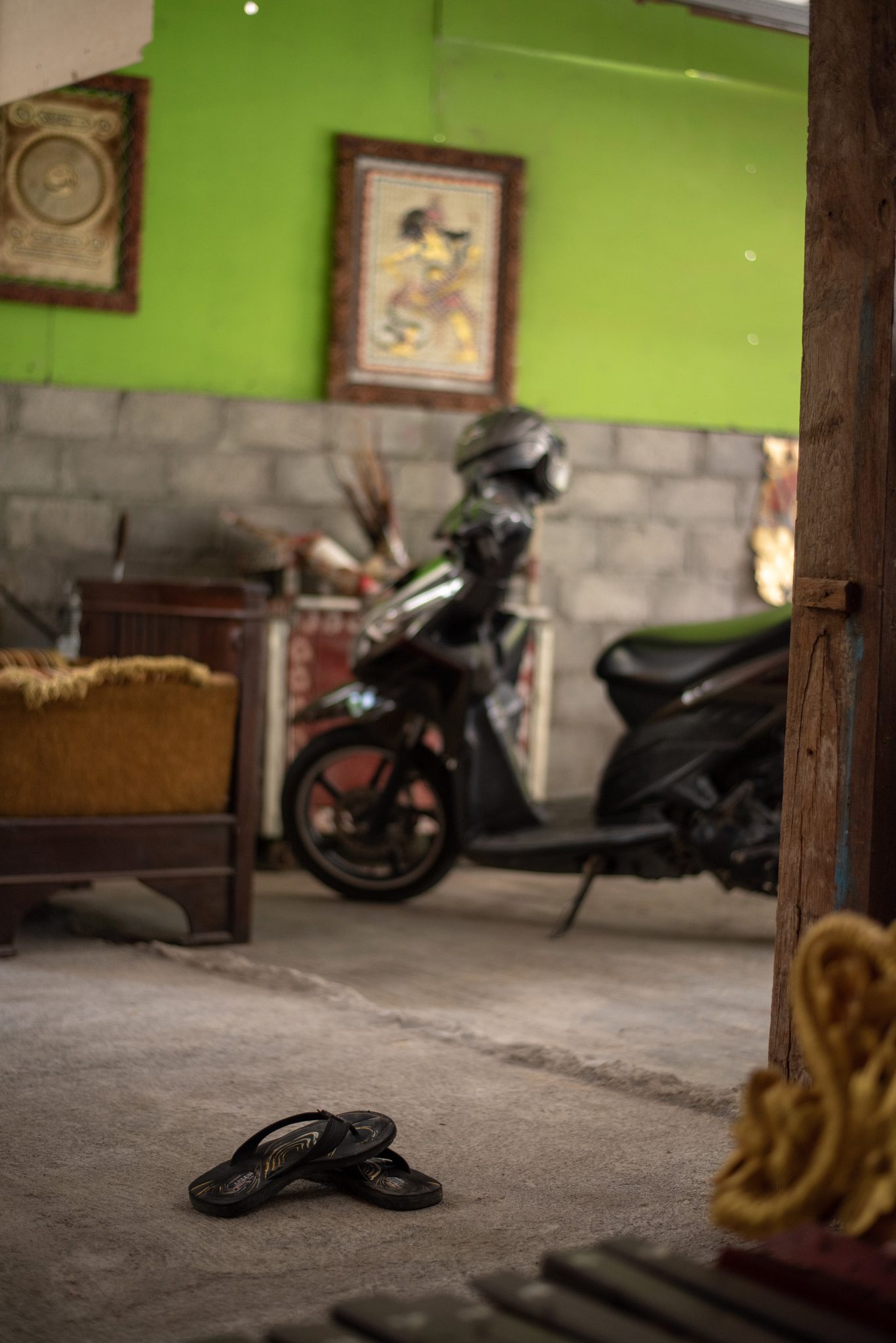 A scooter parked in the front room, sandals left at the door.