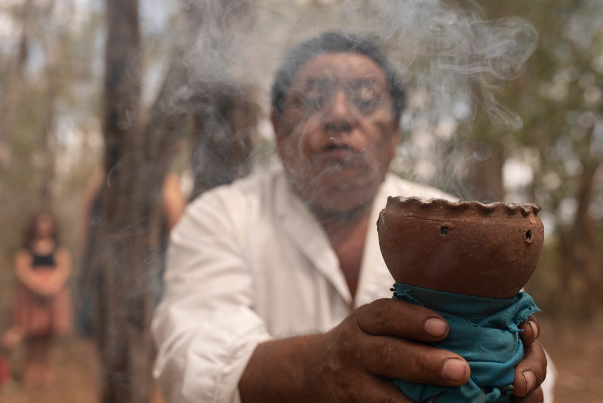Smoke rises from the clay censer as he holds it out.