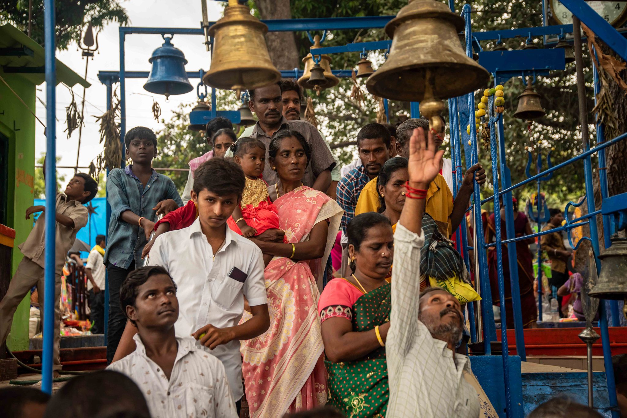 Hands reach up to ring the temple bells as the festival crowd presses in.
