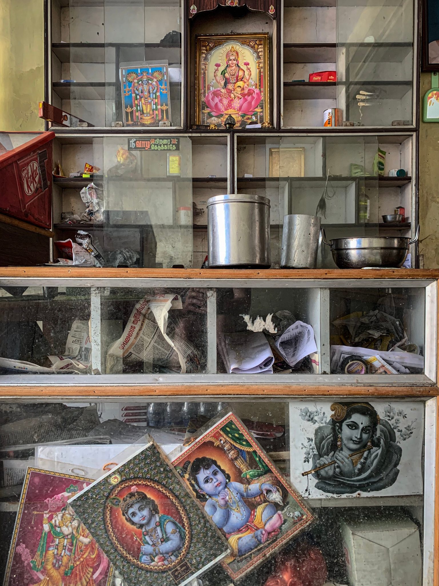 Painted images of Krishna and Lakshmi fill the shelves of a small shop.