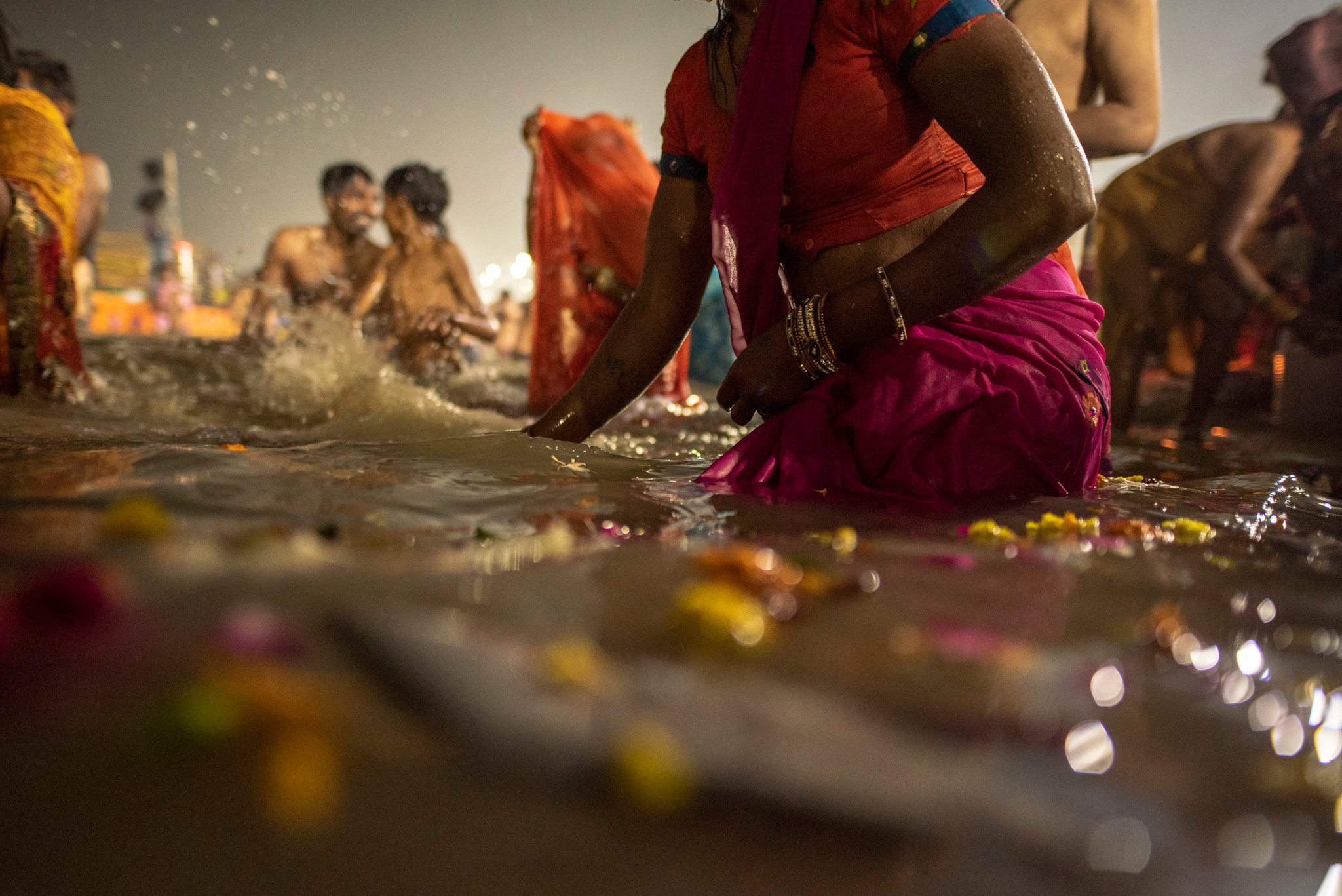 Petals float in the Ganges as men and women gather to bathe