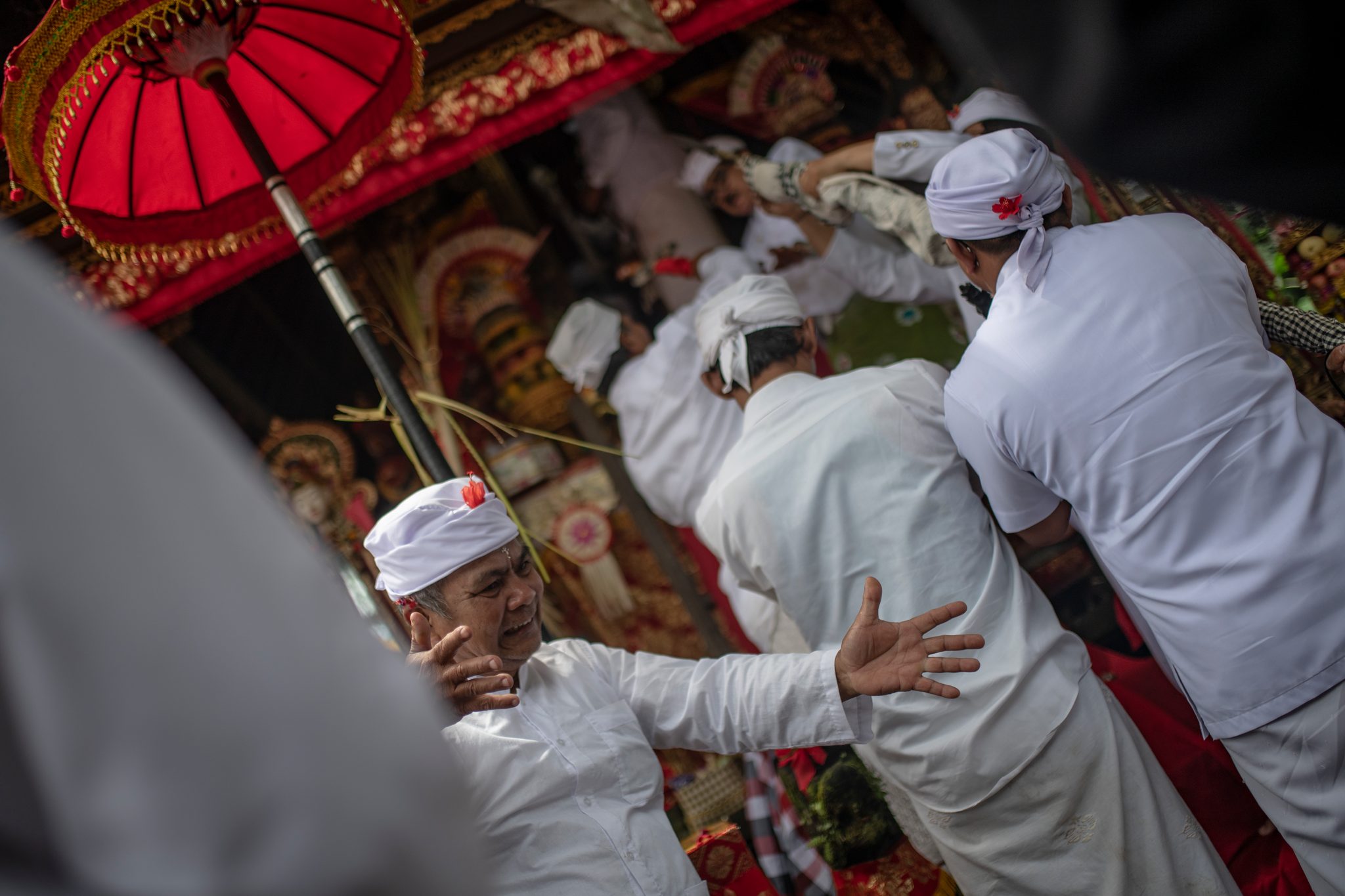 A man reaches out as others steady him at the shrine, the ceremony pressing close around him.