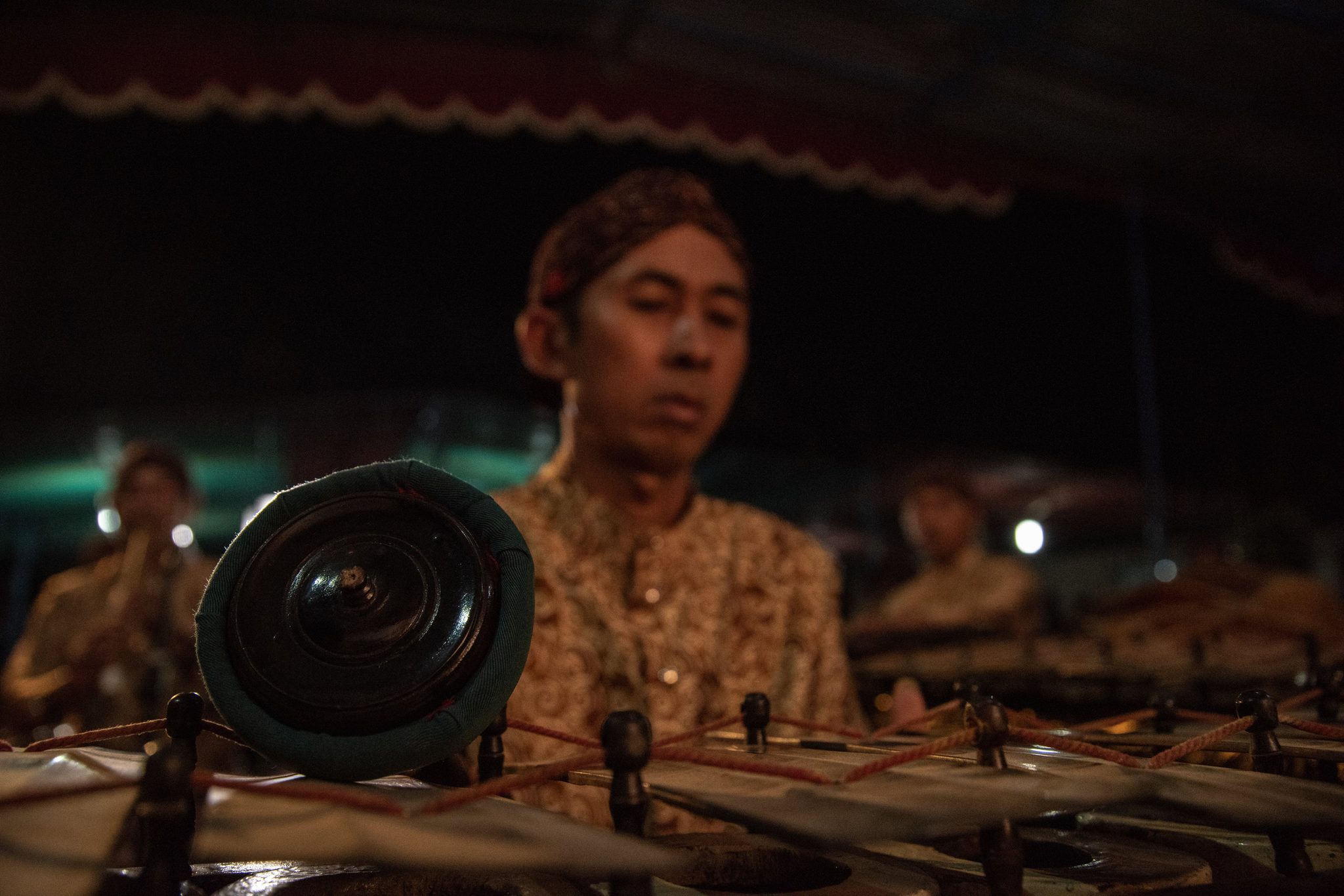 A player waits behind his row of bronze kettle gongs.