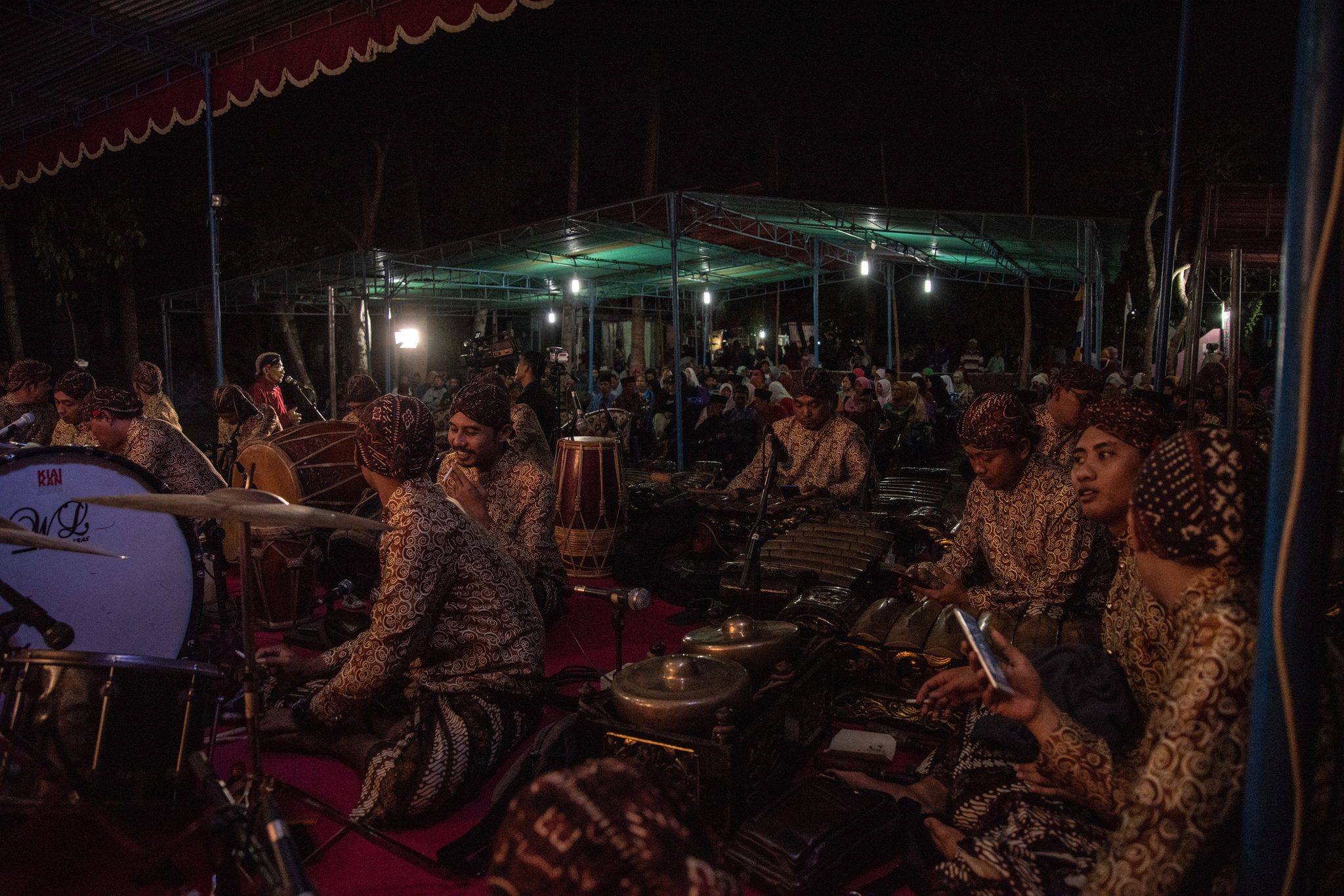 The gamelan orchestra settles in under the tent, the village crowd filling the dark beyond.