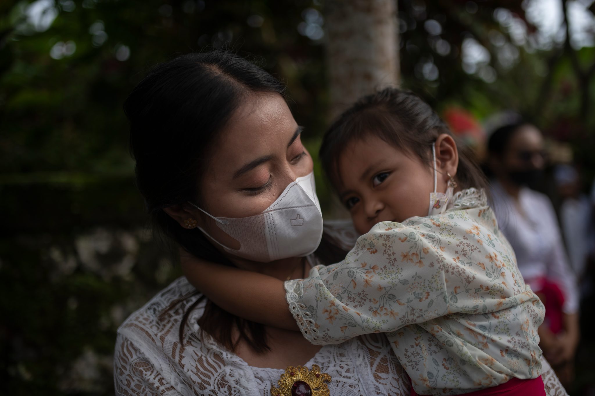 A woman holds a little girl close in the middle of the ceremony.
