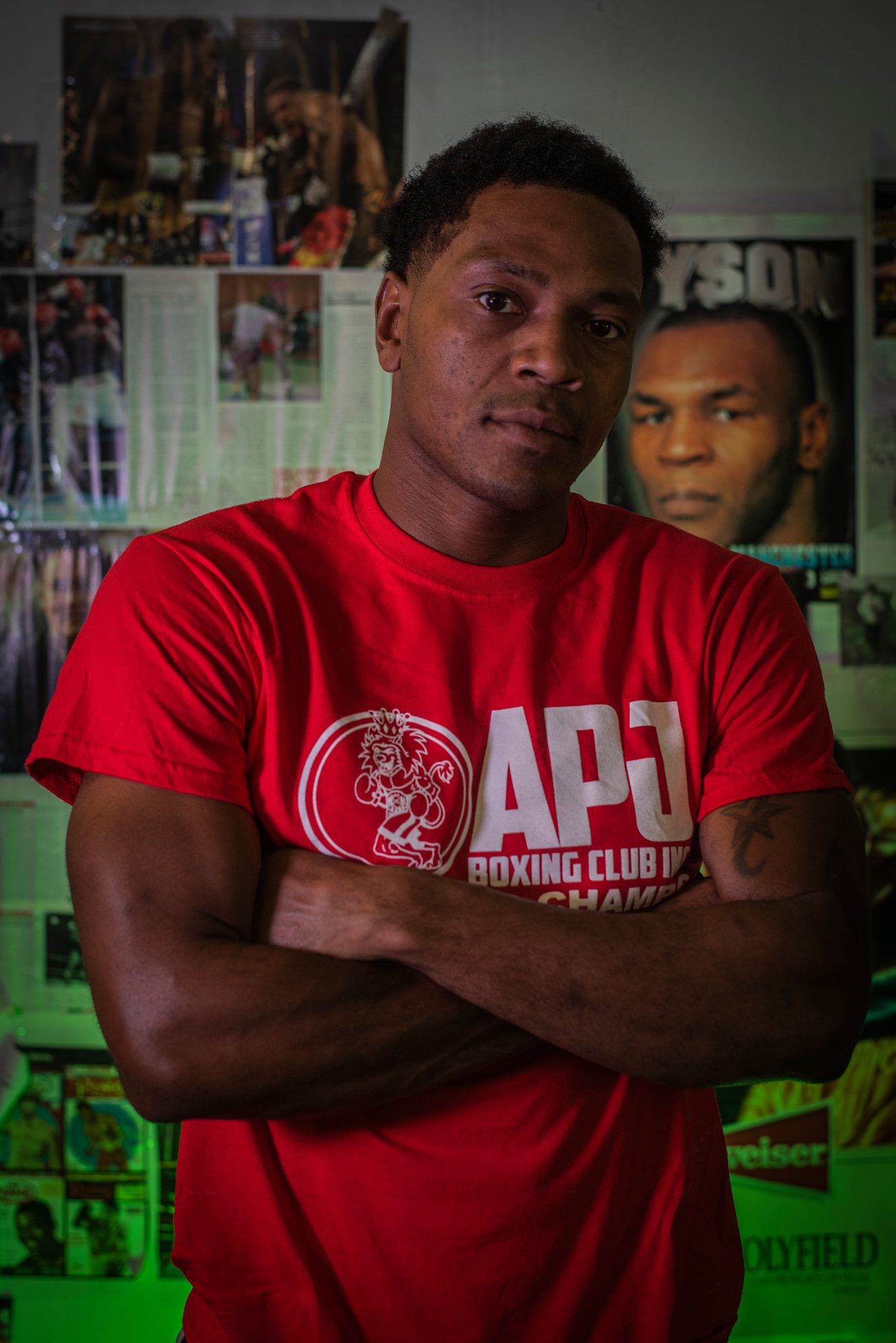 Arms folded across the club logo, he stands square to the lens with Tyson's face over his shoulder.