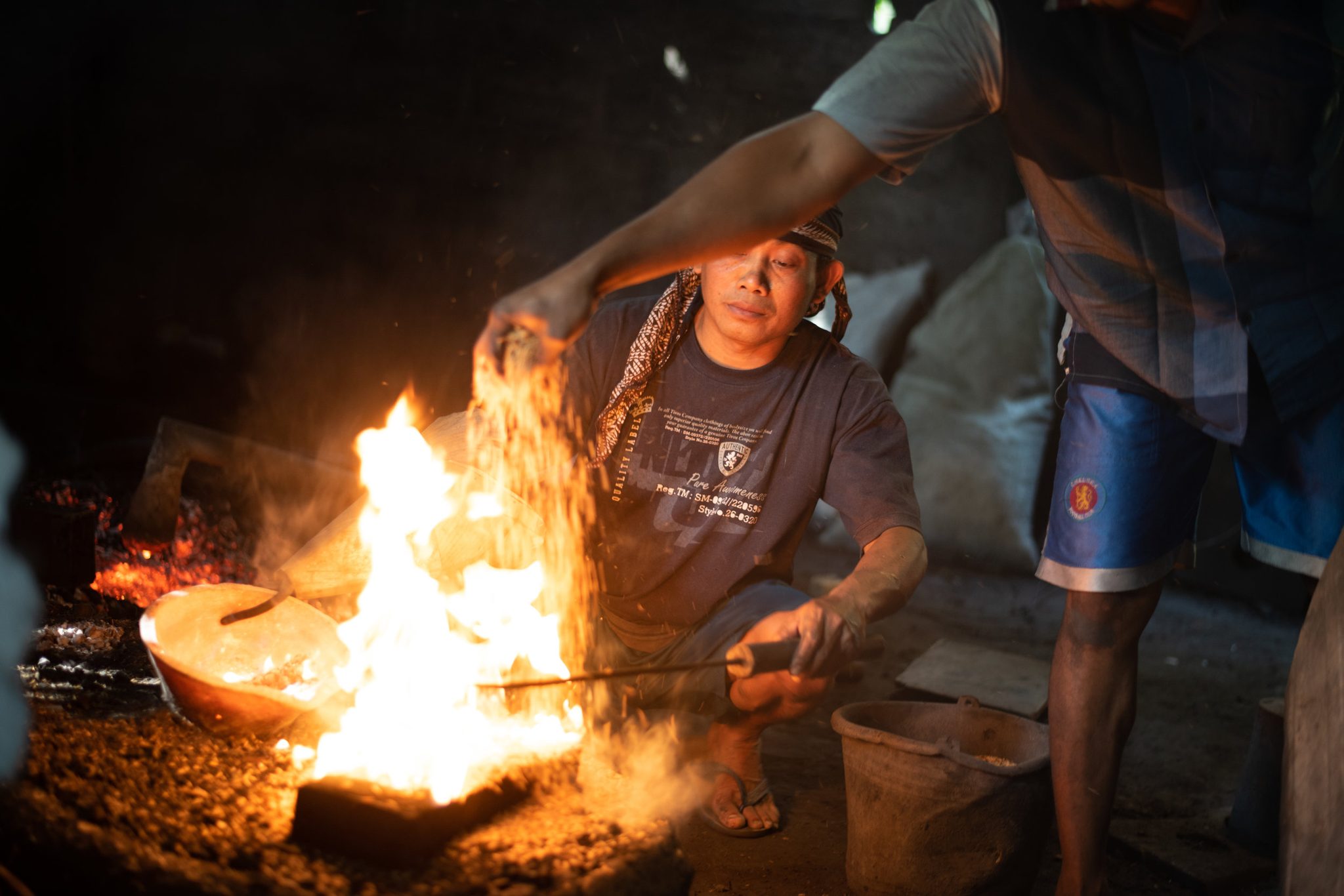 Molten metal pours from the crucible into the mold as the fire leaps up around it.