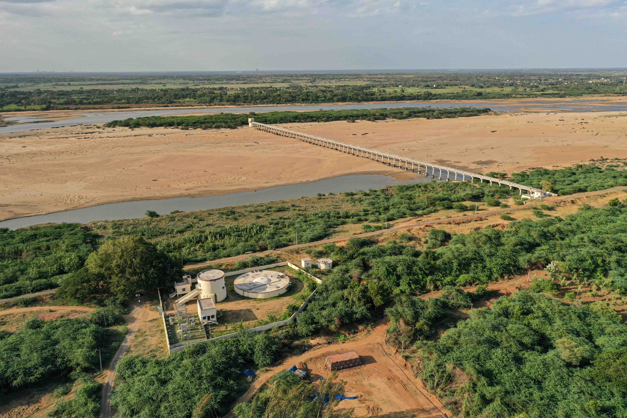 The bridge runs out across the wide, dry riverbed.