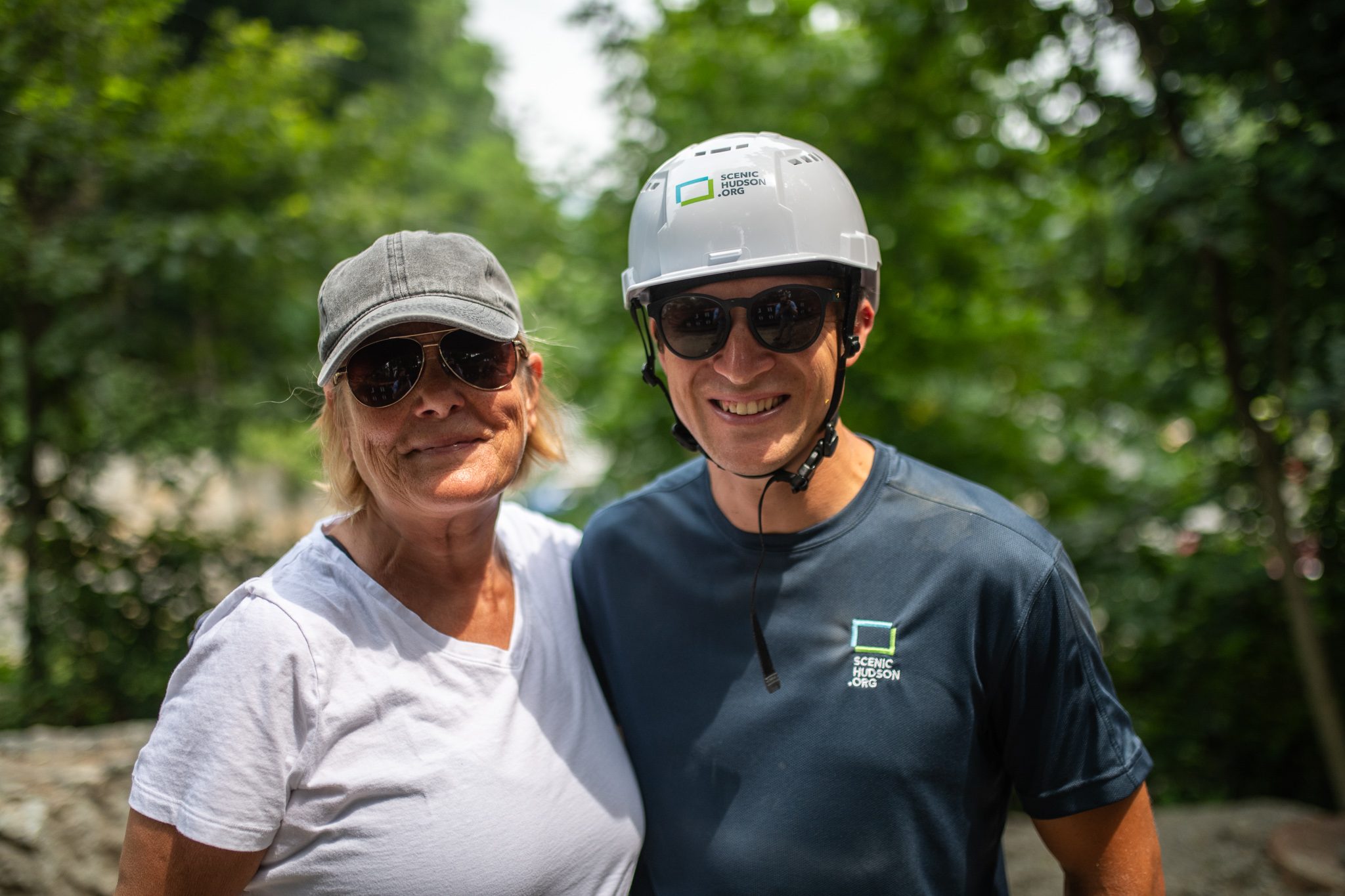 A visitor and a crew member share a grin in the shade.