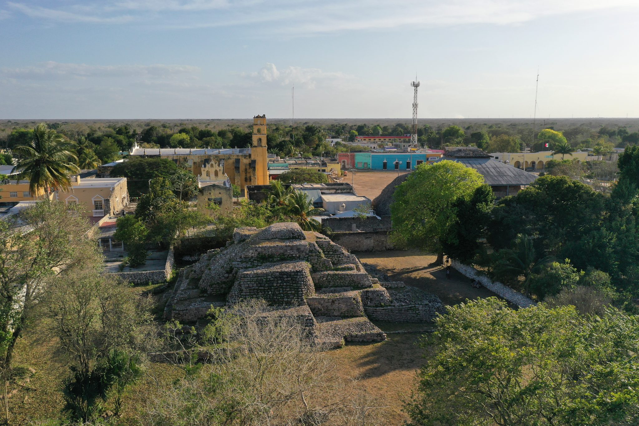From above, the stepped ruins of a pyramid sit in the middle of town, the yellow church just beyond.
