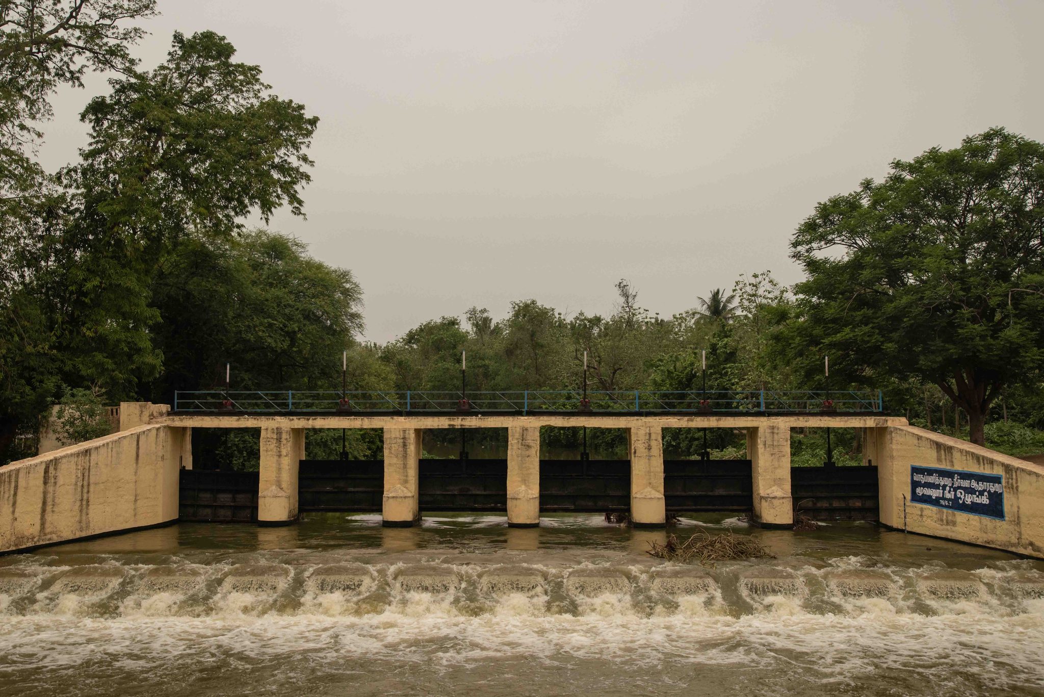 Water pours through the gates of a small dam.