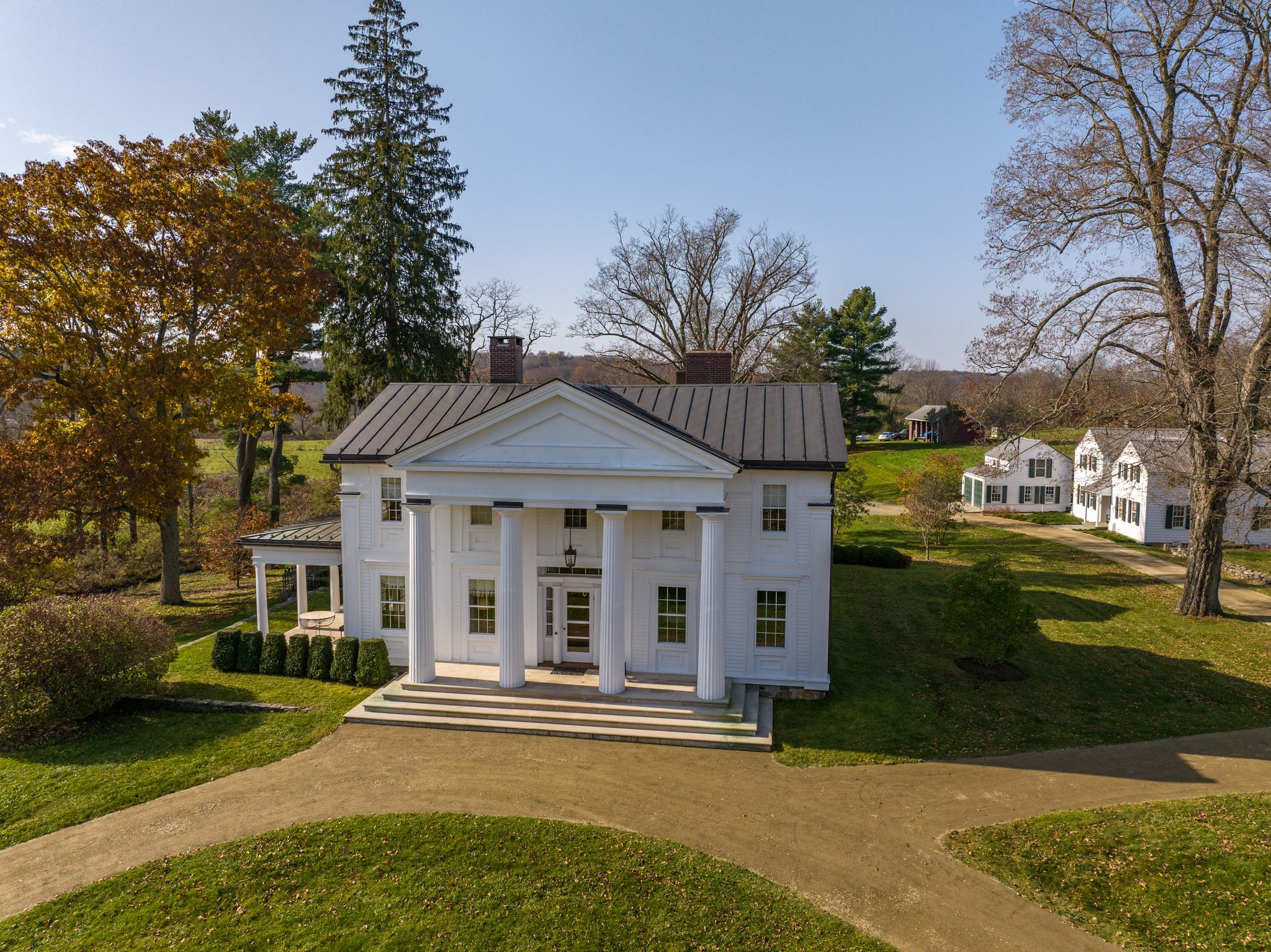 Morning in early November finds a columned Greek Revival house and its outbuildings settled into lawns still green.