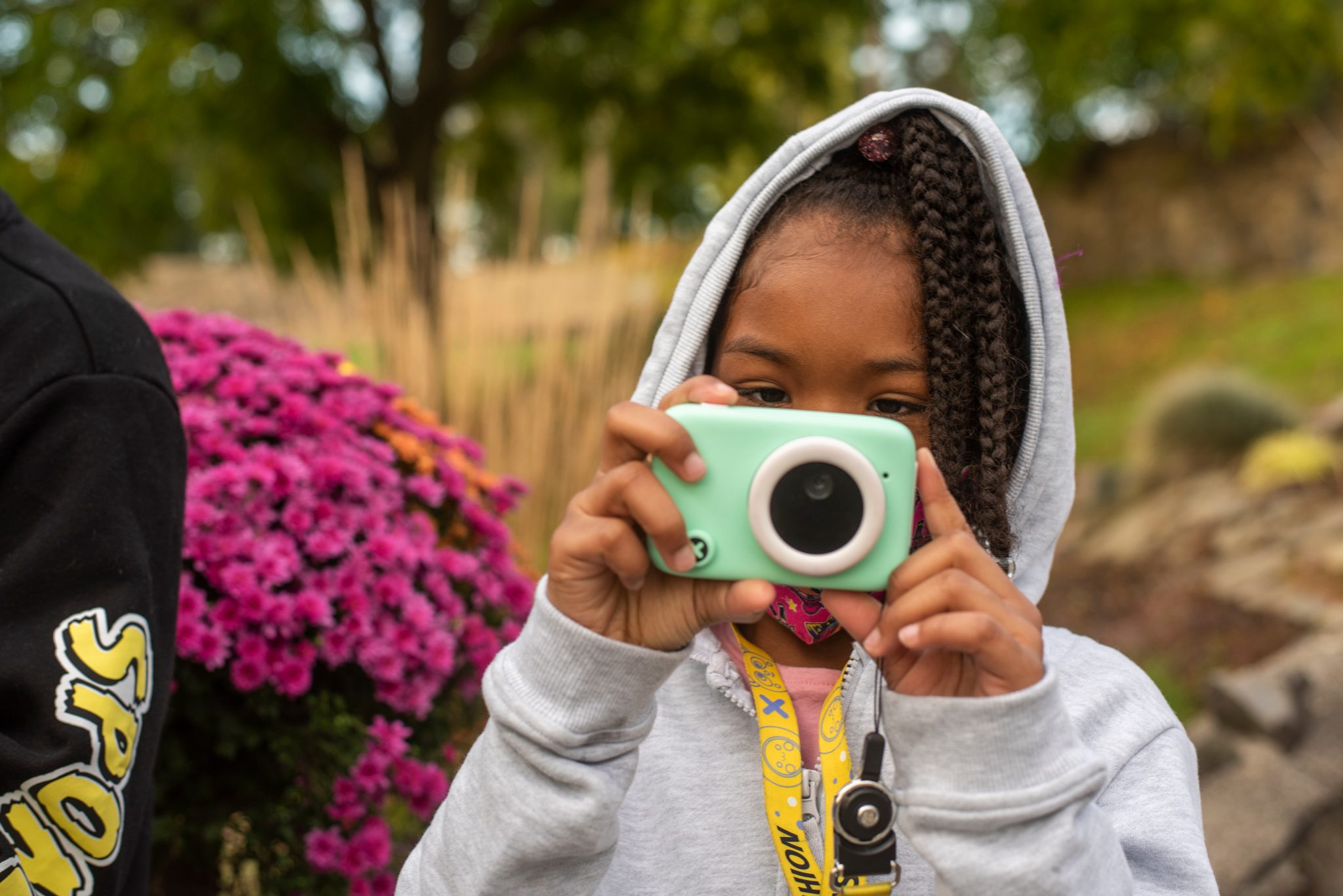 A young photographer settles in low beside the mums, waiting on her frame.