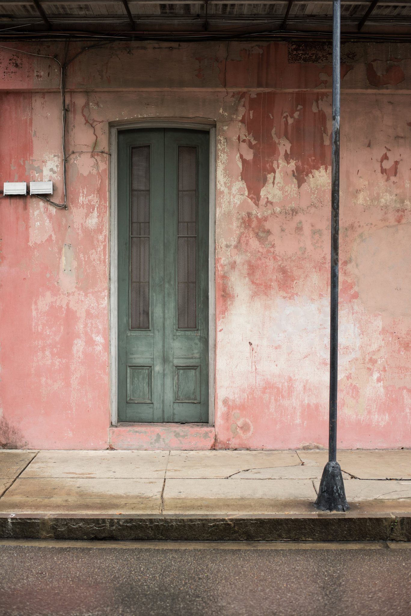 A green door in a faded pink wall.