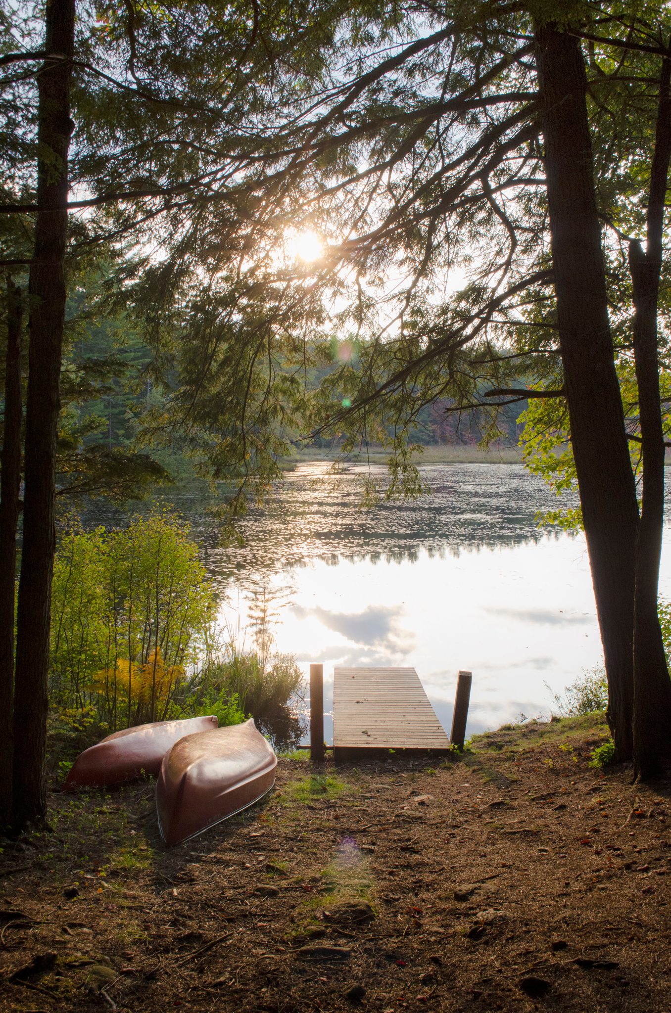 Canoes rest beside the dock as the sun sets over Lowell Lake.
