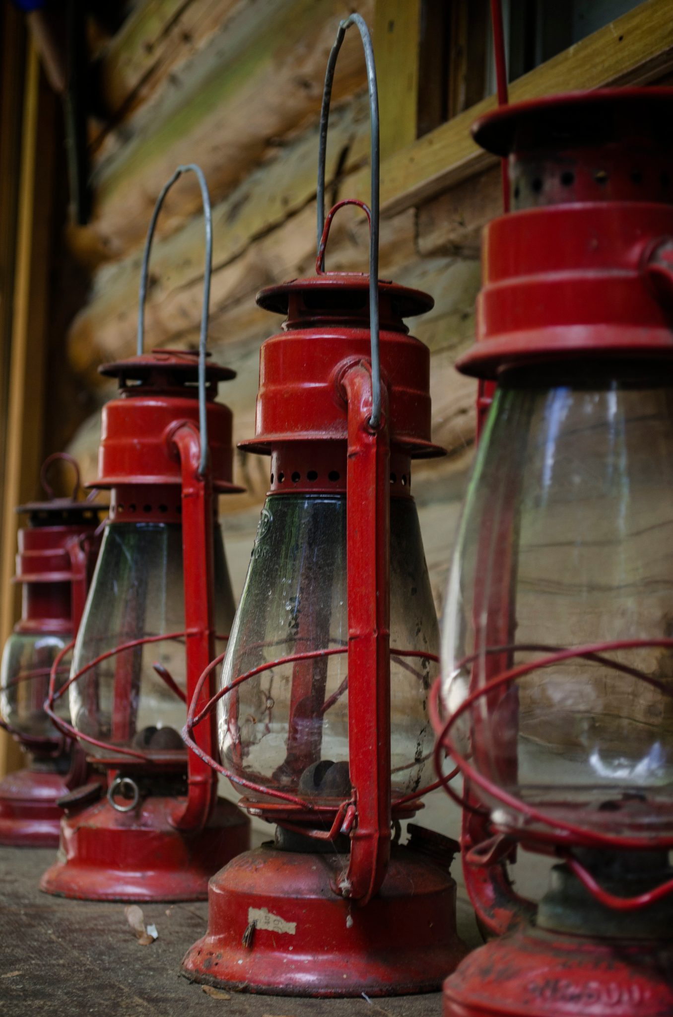 Red lanterns lined up on the porch of a log cabin.