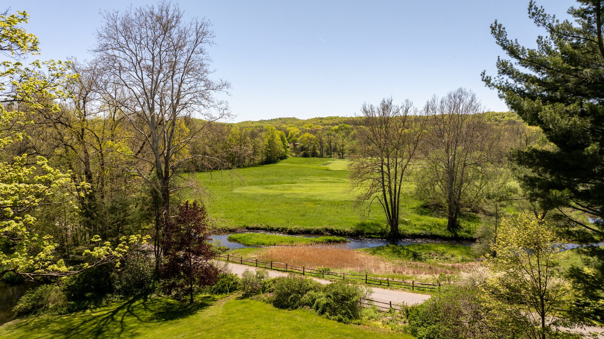 From above the lawn in early May, the meadow runs out to the stream and the hills still wear their first green.