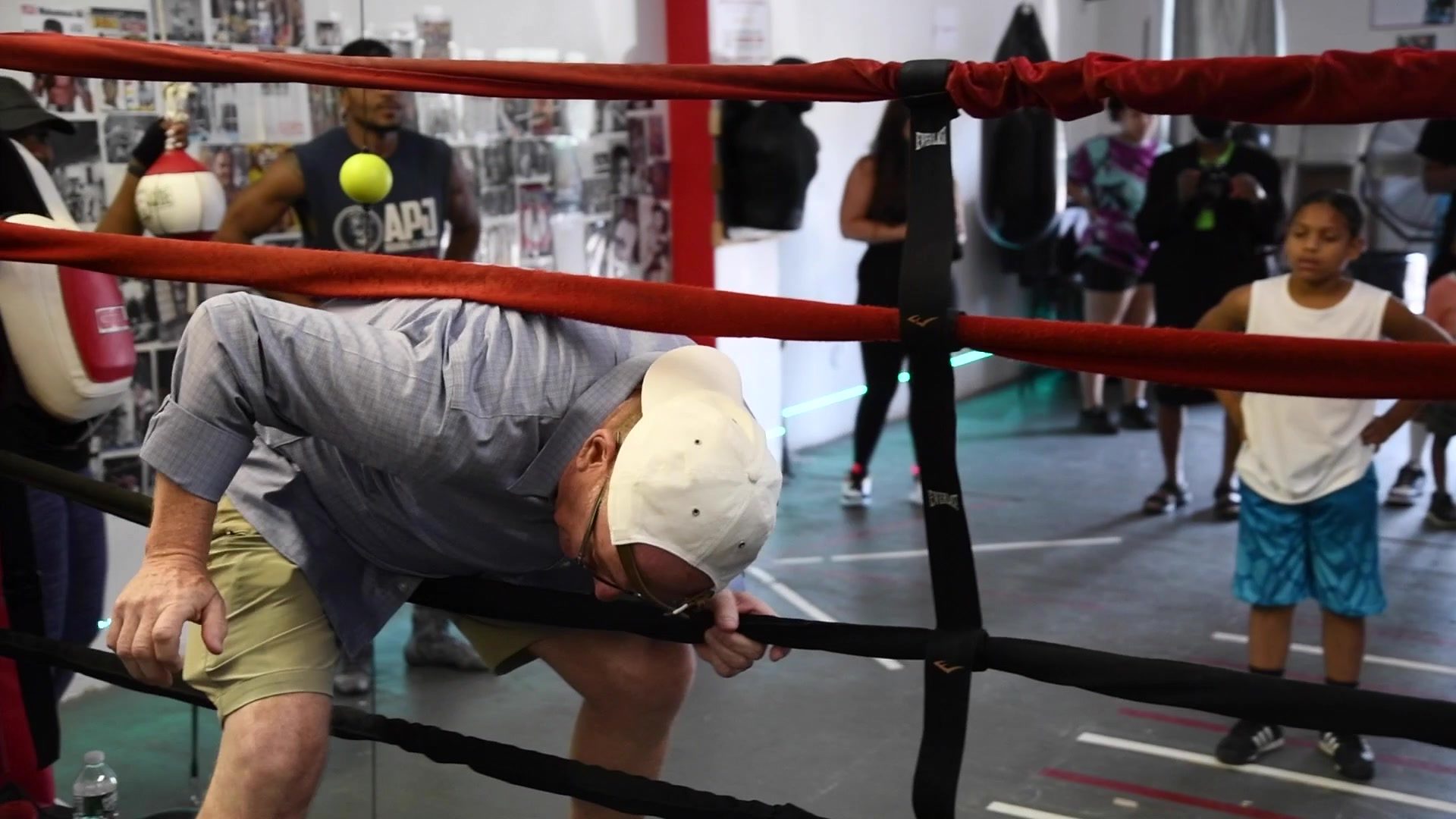 A guest in a button-down ducks through the ropes for his turn as kids watch from the back.