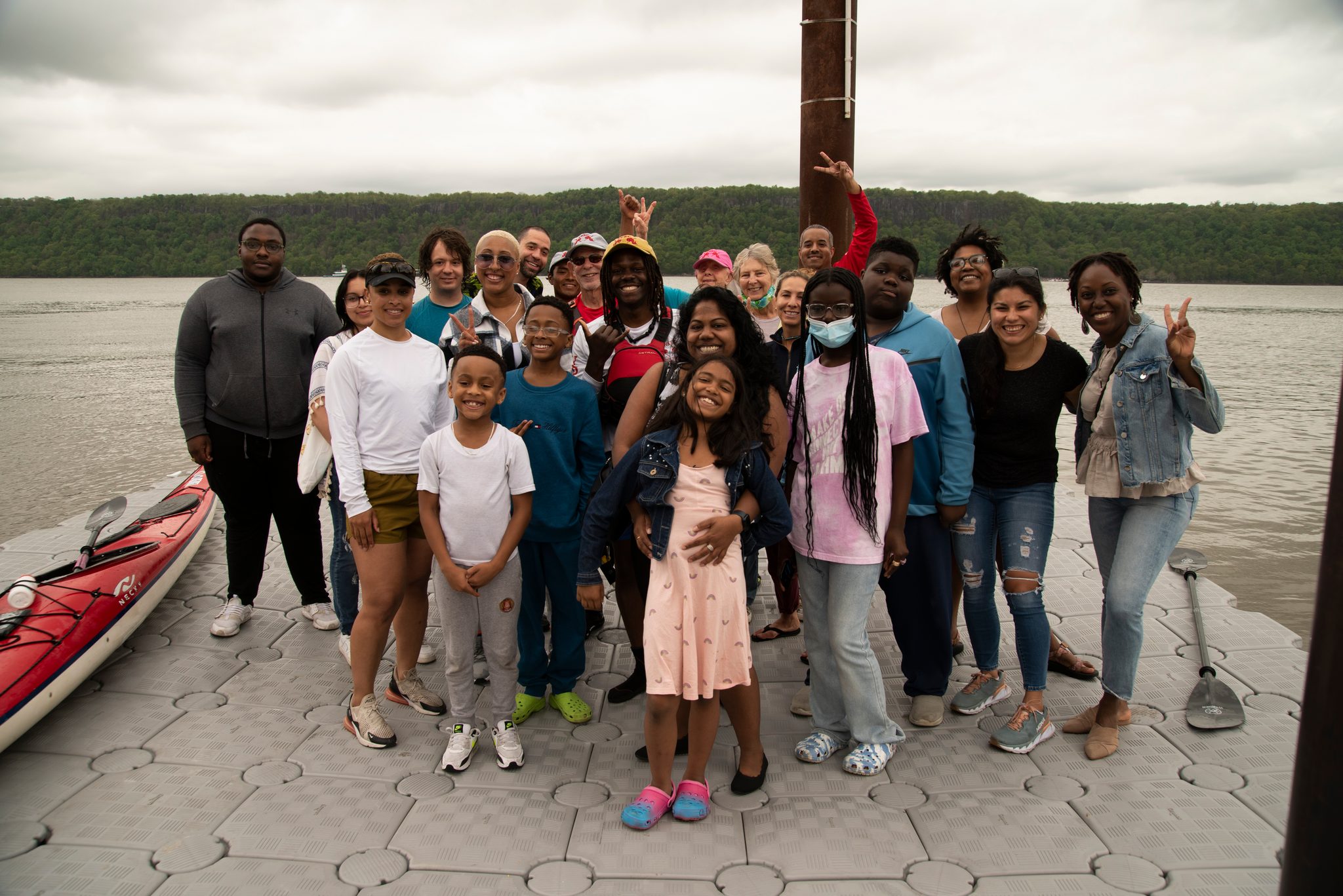 Families line the floating dock for a group photo, kids up front, the far shore wooded behind them.