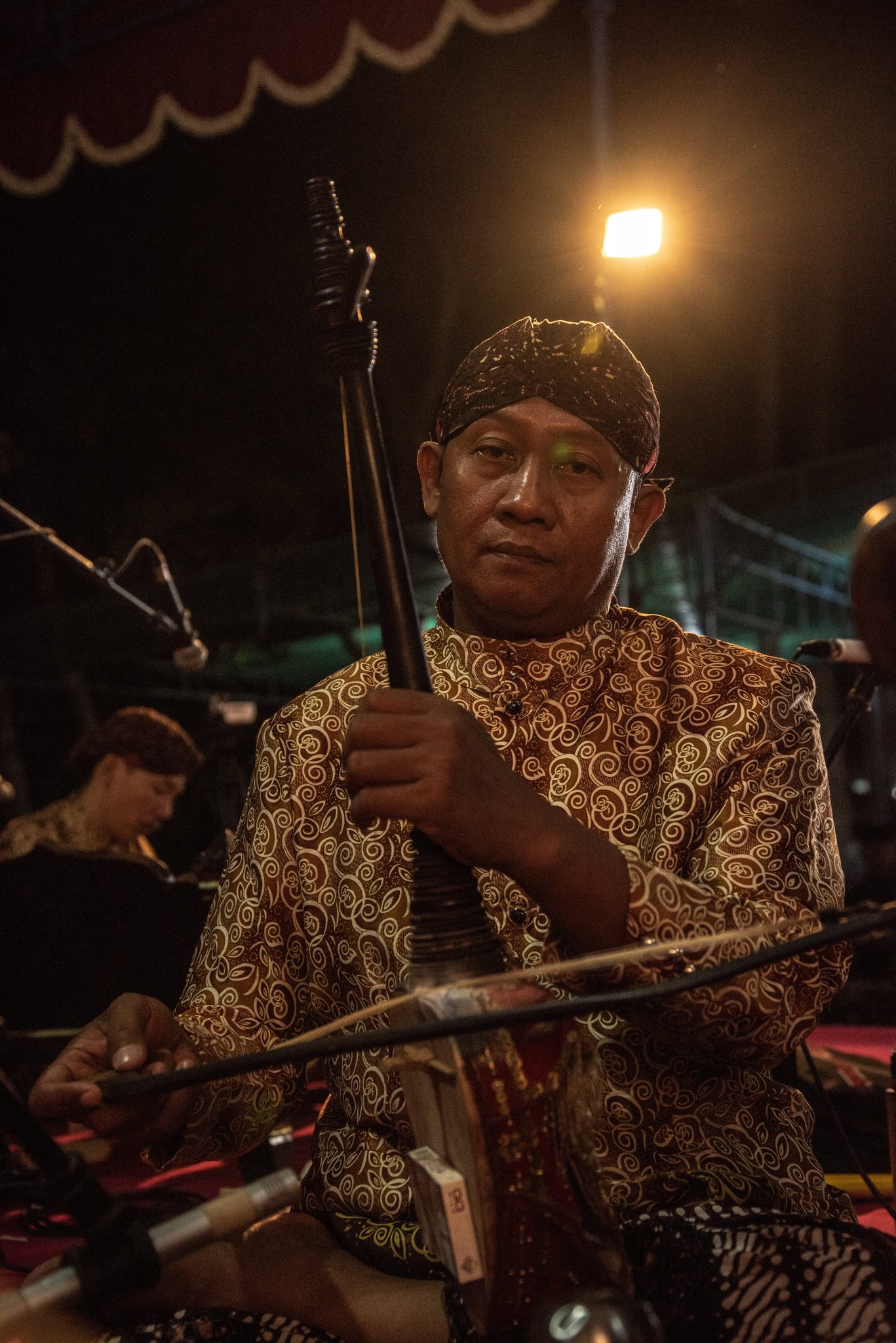 A musician draws his bow across the rebab, the two-stringed fiddle of the gamelan.