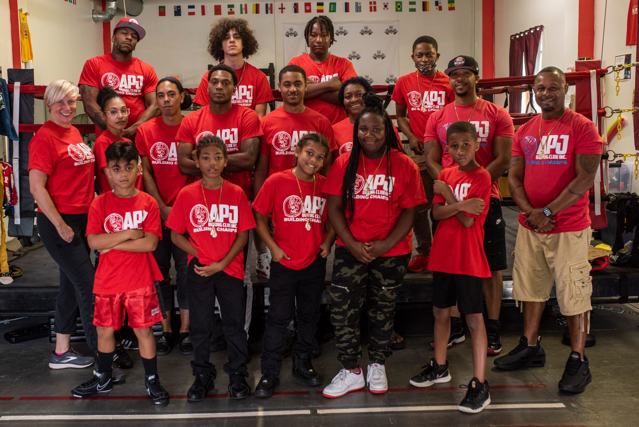 The whole club in red lines up in front of the ring, kids up front and Coach Kariym at the far right.