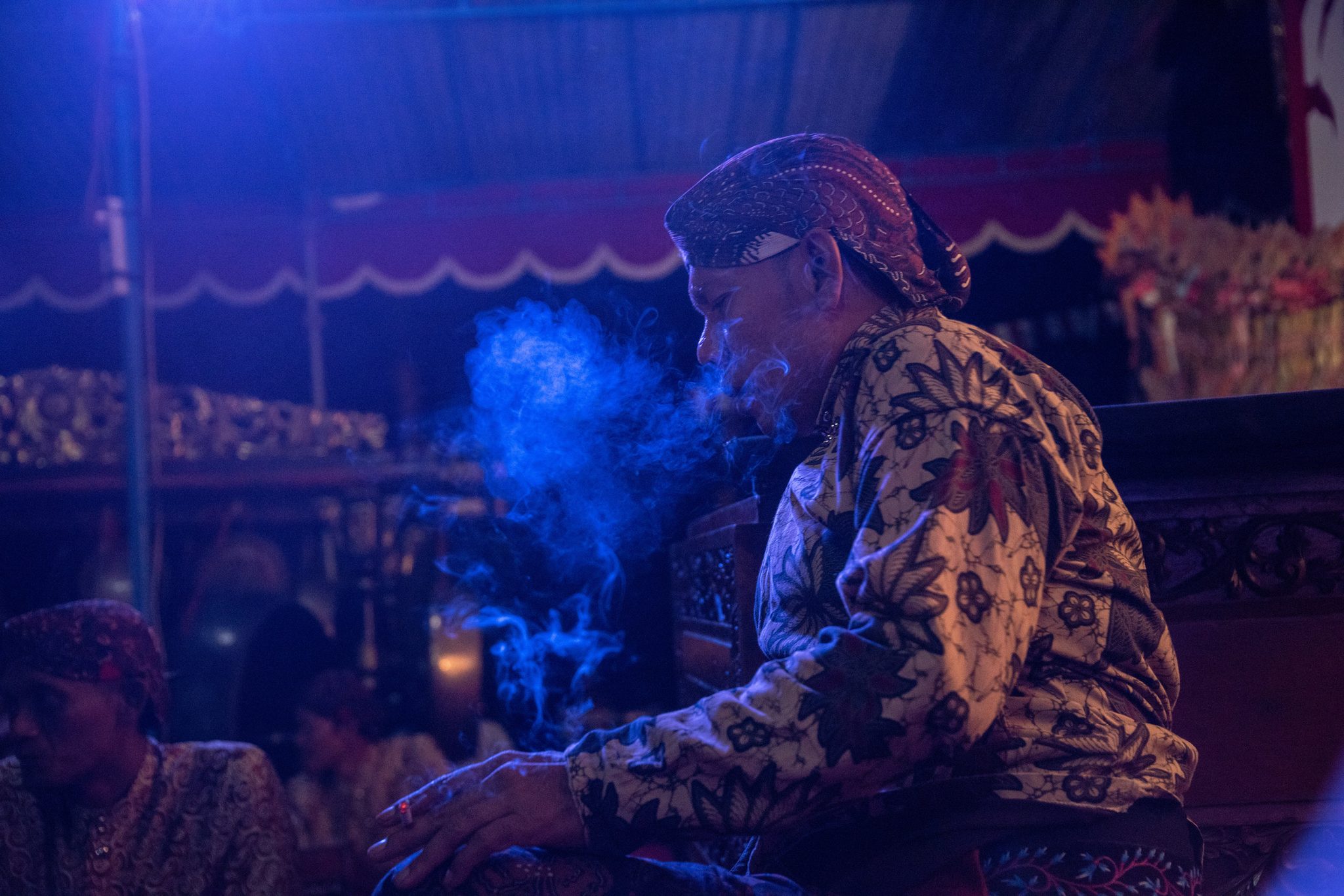 A performer exhales a cloud of smoke into the blue stage light.