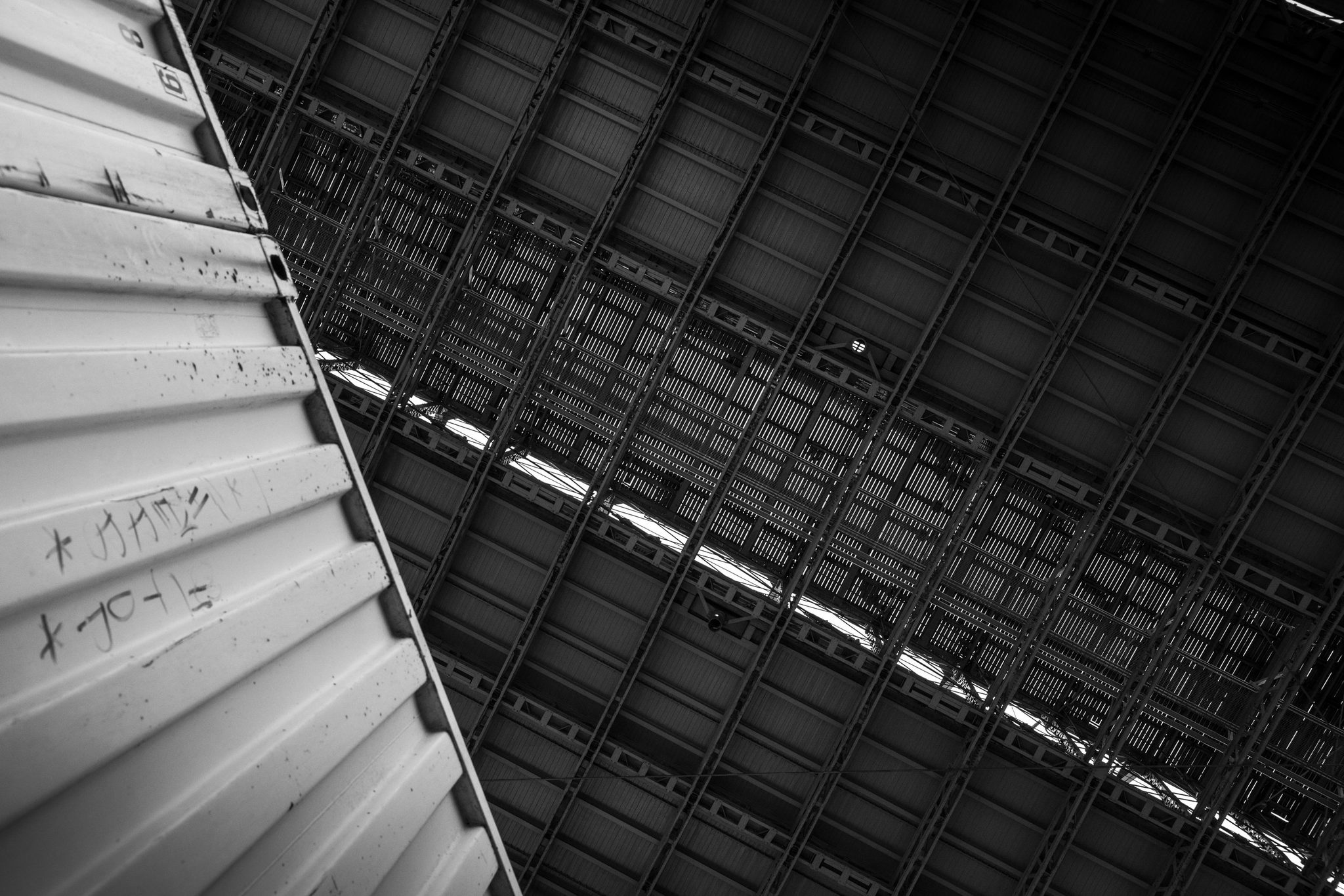 A stairwell's steel ribs and a scrawl of graffiti, in black and white.