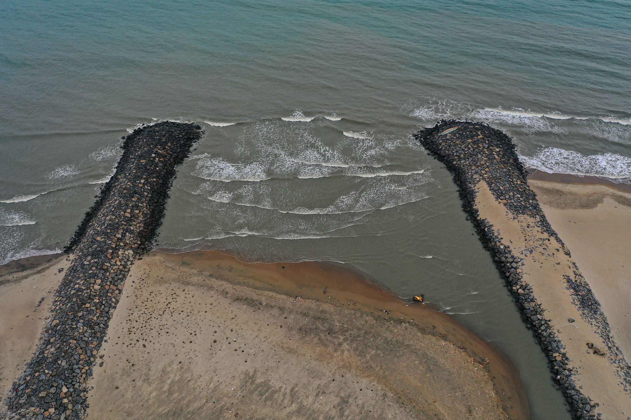 From above, two breakwaters guide the river into the sea.