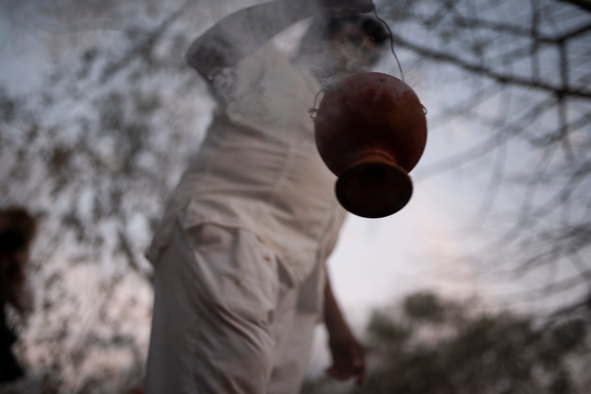 A clay censer swings from a cord, trailing smoke.