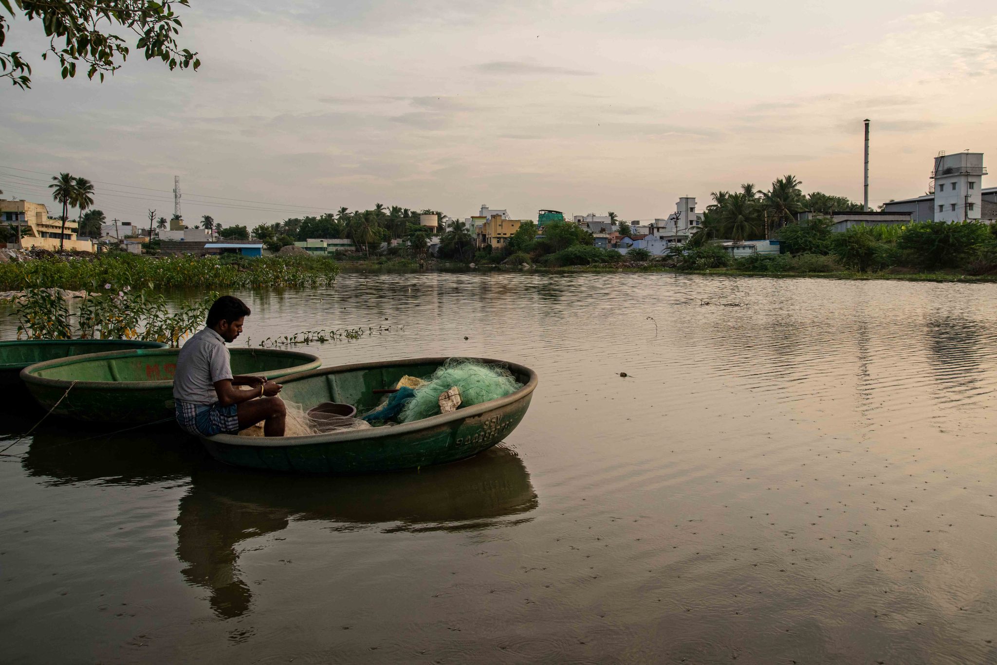 A man sits in his coracle as the evening settles over the town's edge.