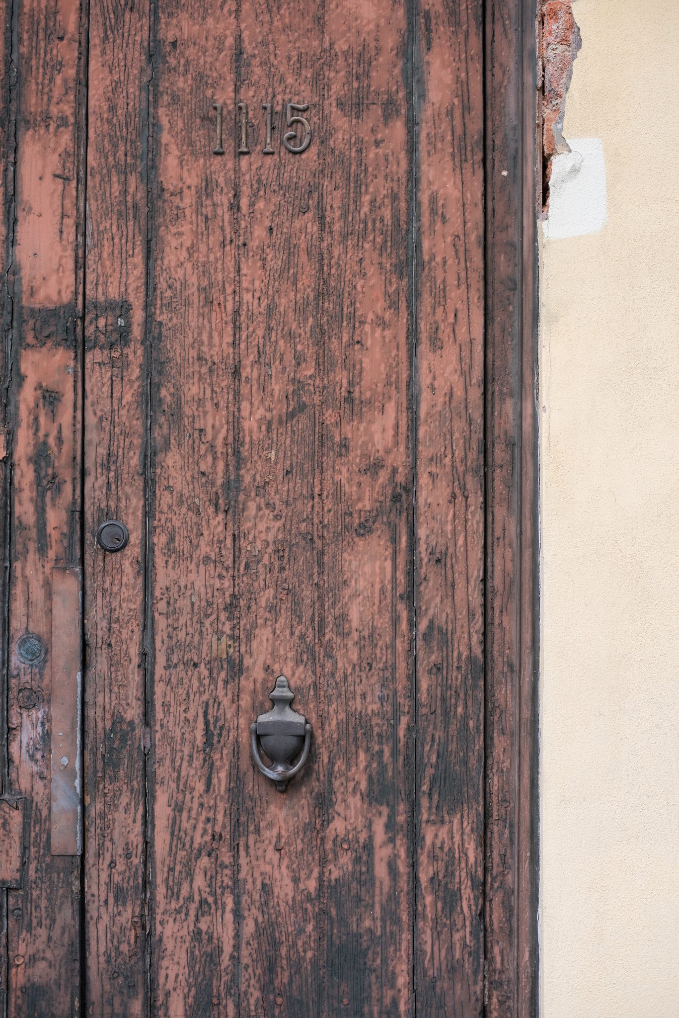 A weathered door, its number carved into the wood: 1115.
