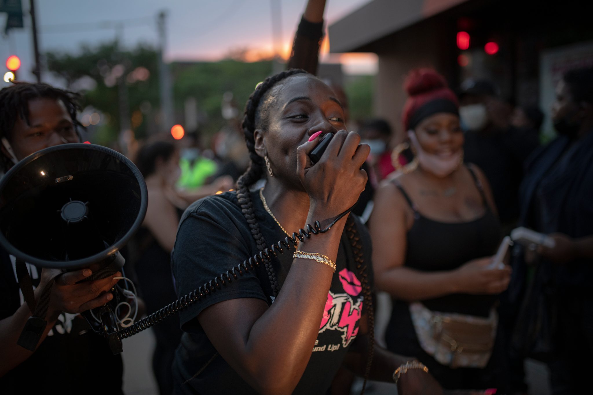 A woman leads the chant into the megaphone, the women beside her smiling.