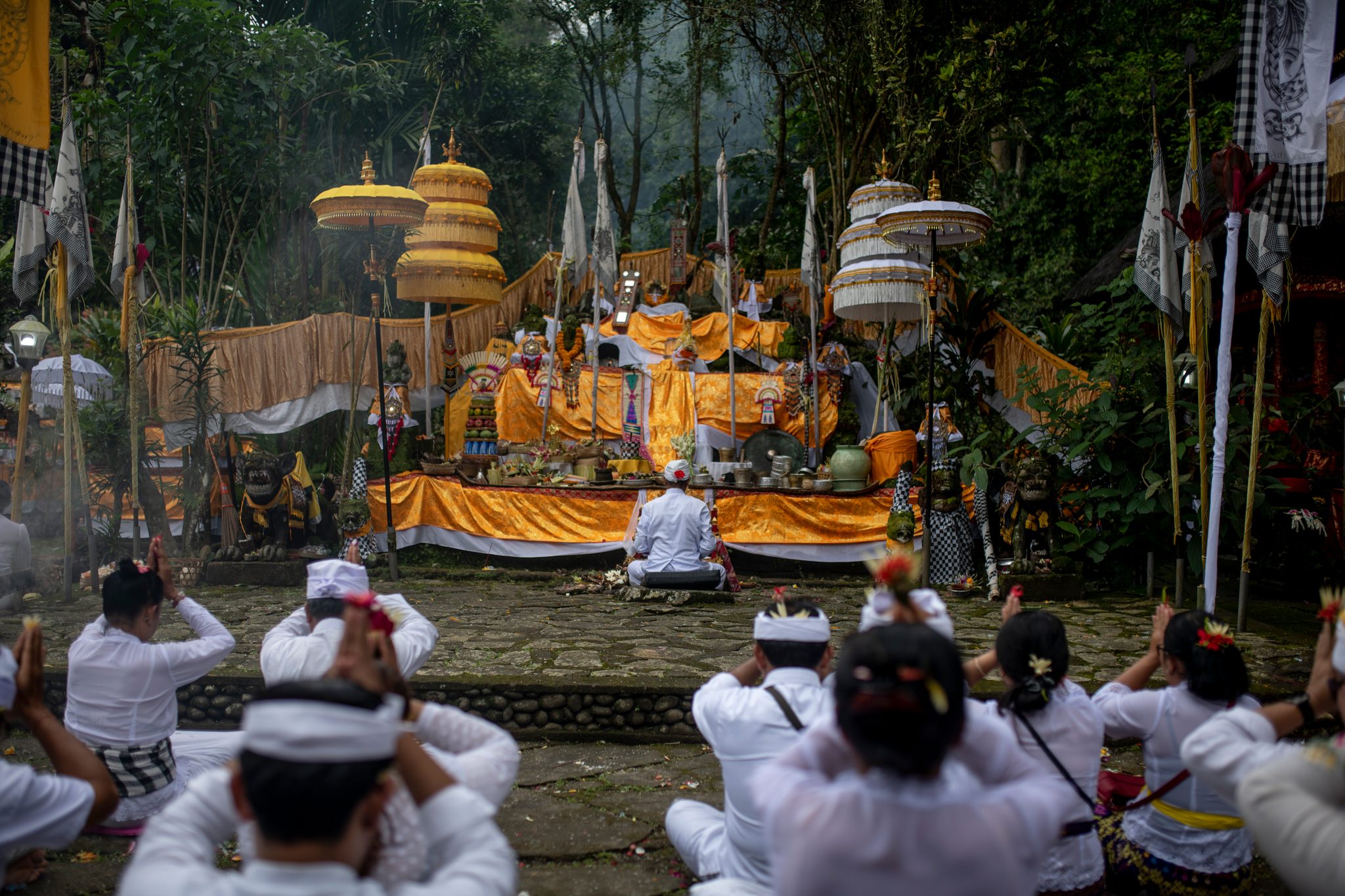 Hands rise to foreheads in prayer as incense drifts across the golden shrine.