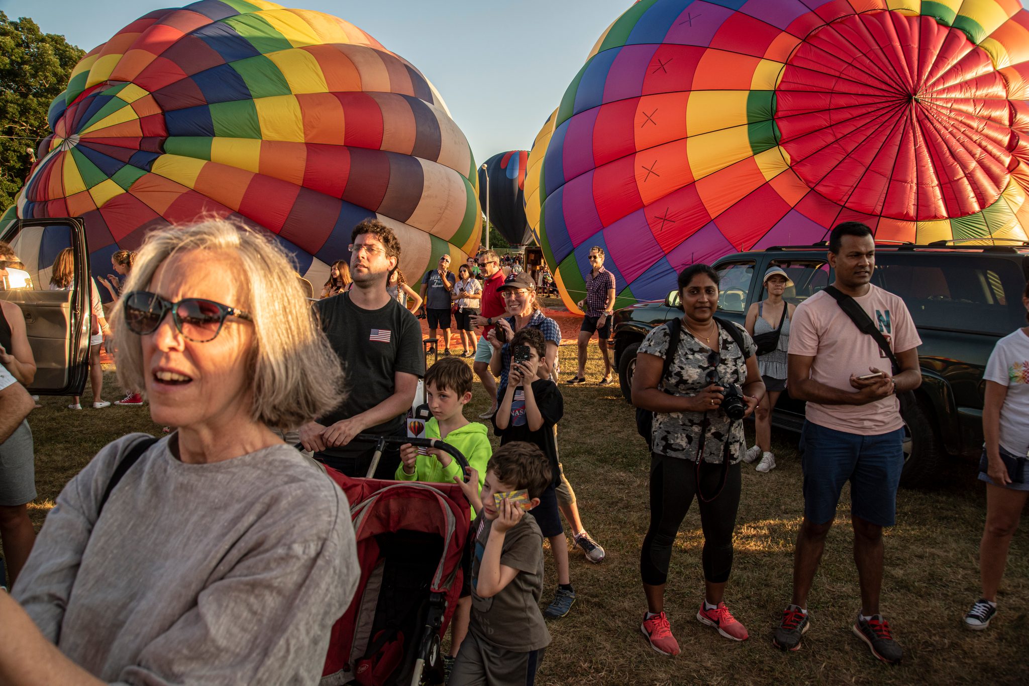 The crowd looks up as the envelopes fill, a woman in sunglasses caught mid-wonder.