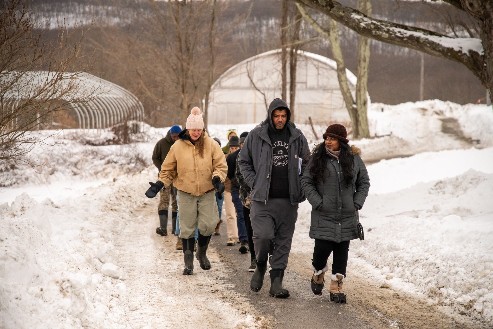 A walking tour heads out past the hoop houses on a packed snow path.
