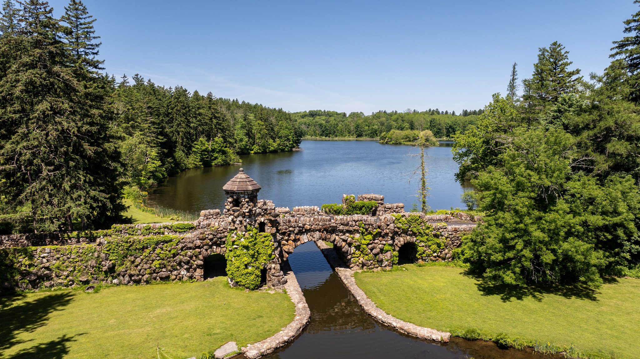 A rough stone bridge with a turret spans the outlet of the lake, the water slipping through its arch.