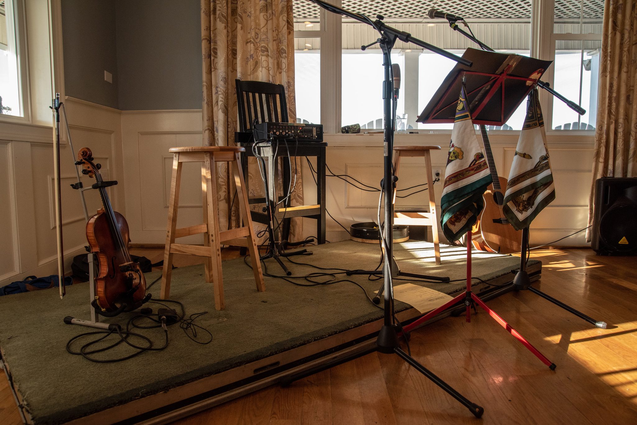 Before the house fills, the stage waits: two stools, a fiddle on its stand, the mics already set.
