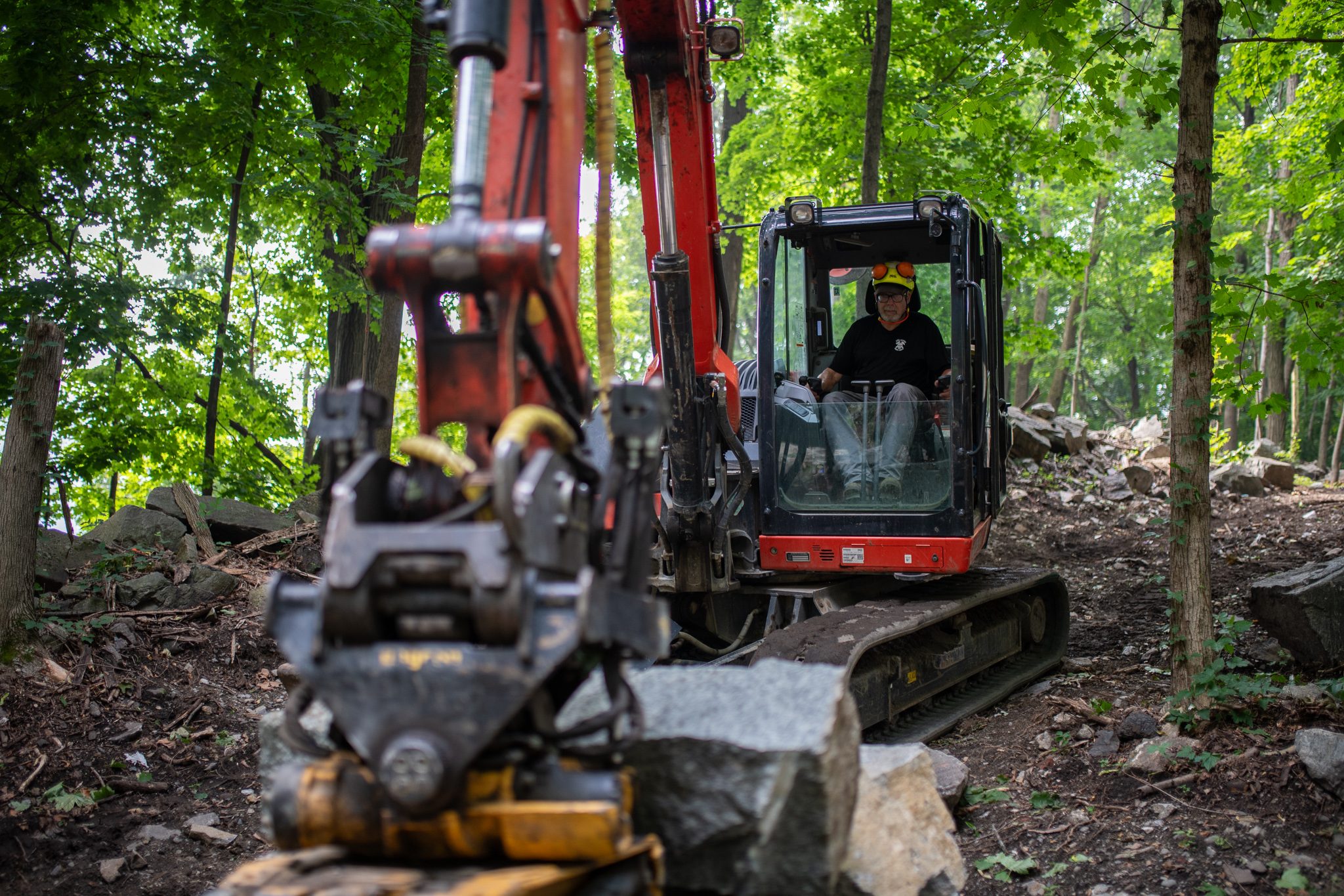 The operator watches from the cab as the grapple sets a stone down.
