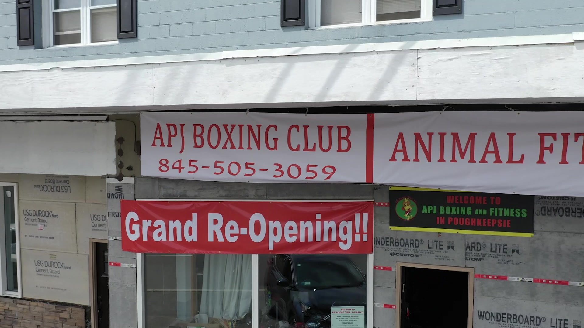 Fresh banners over the door: the club's name and number, a Grand Re-Opening sign, and a welcome to Poughkeepsie in the window.