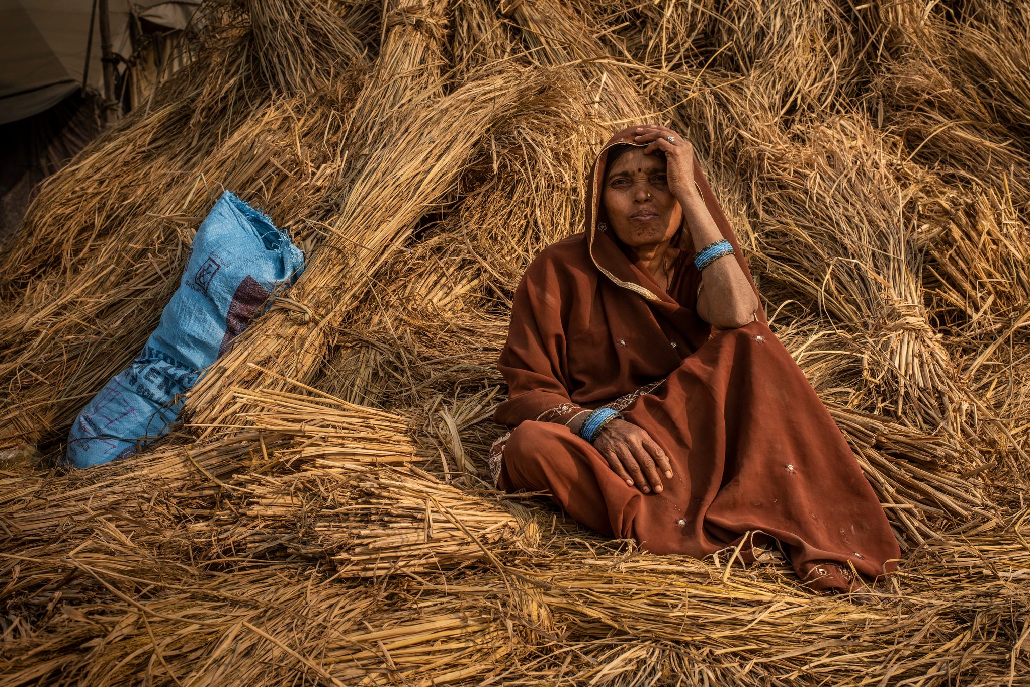 Woman rests on a bale of hay.