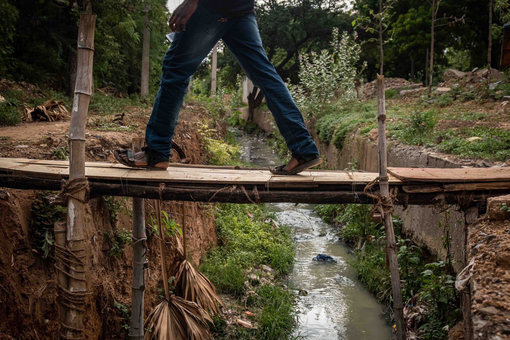 A man in jeans strides across the same narrow bridge.