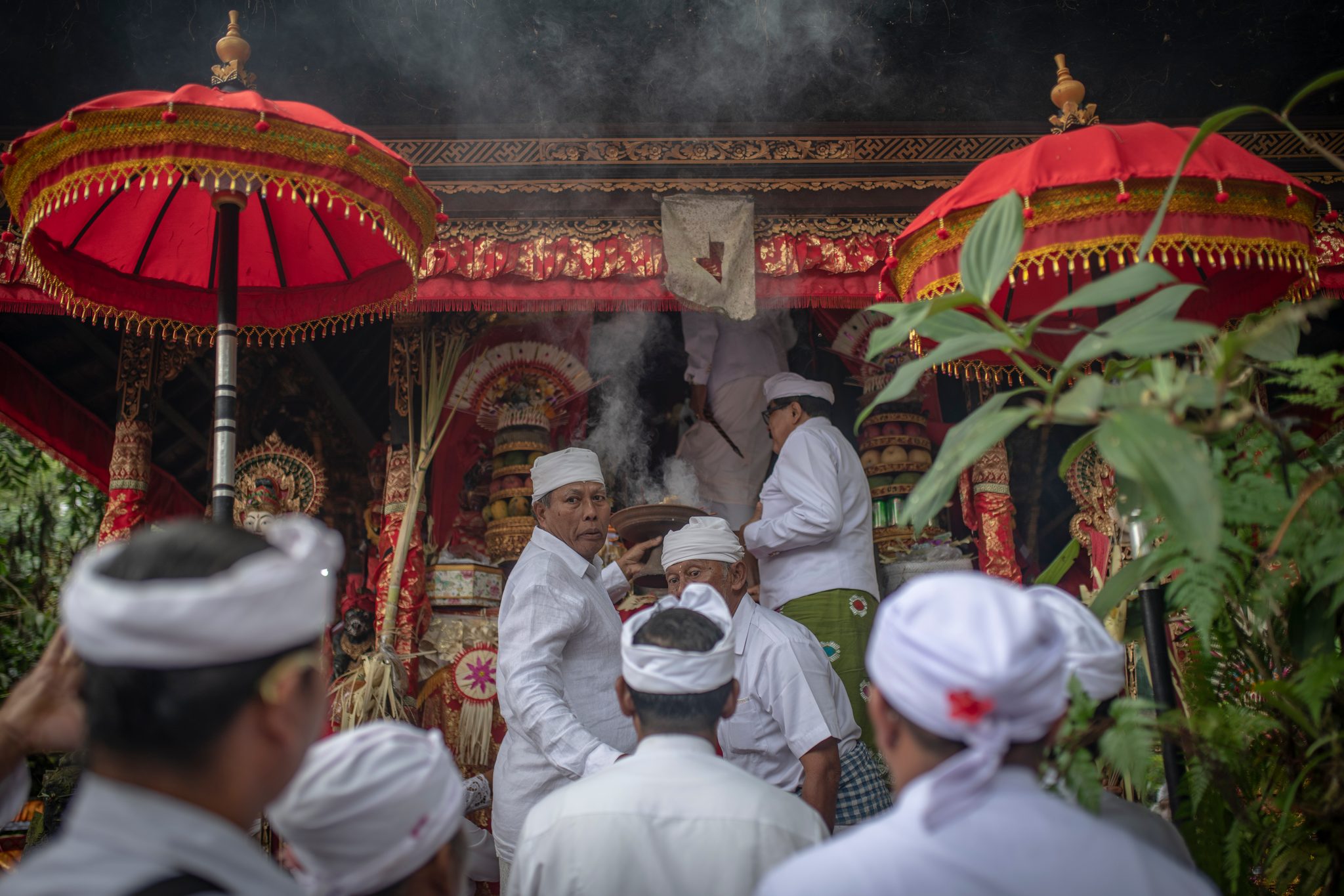Smoke rises from the red and gold shrine as the priests tend the offerings inside.