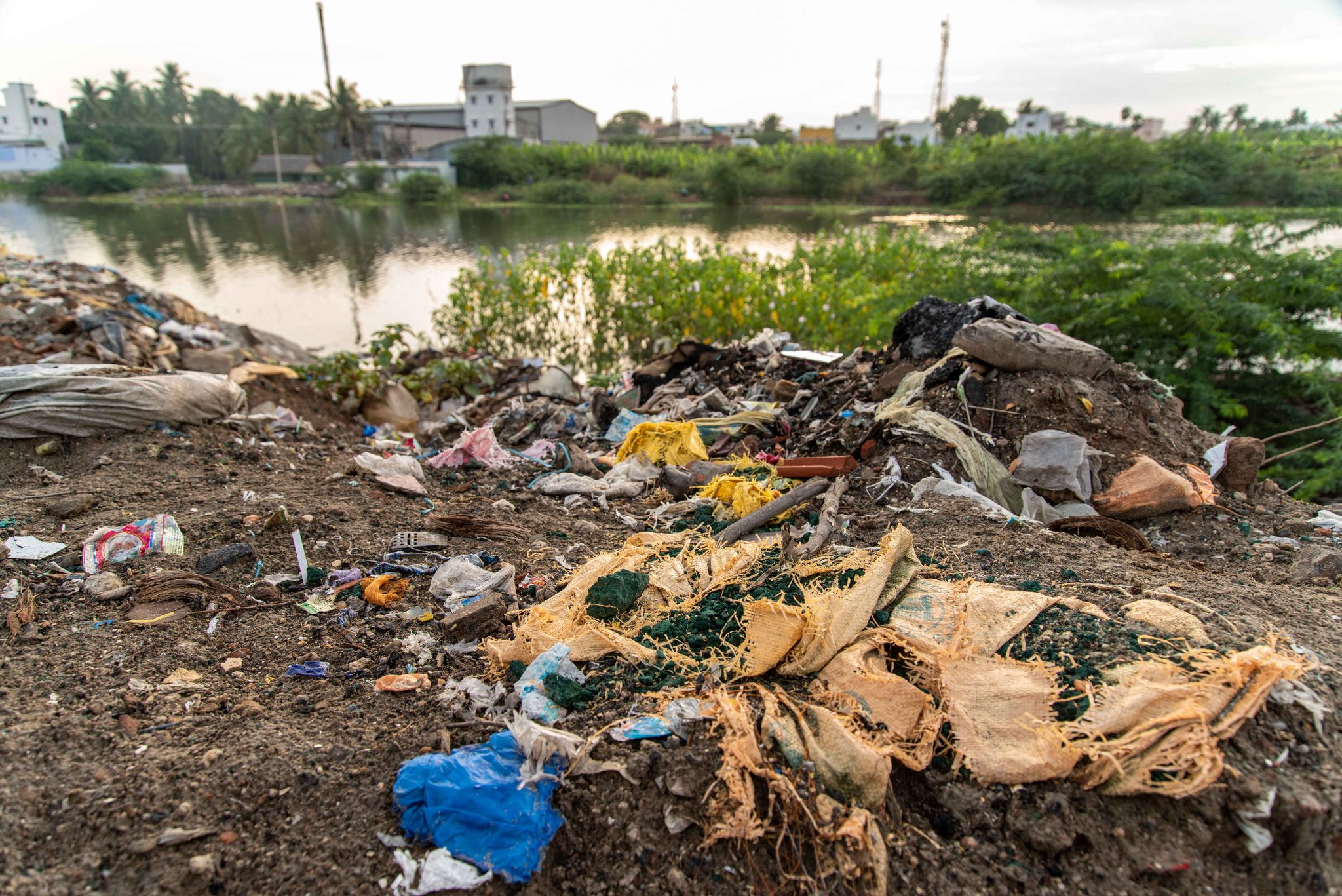 Rubbish spills down the bank to the water's edge.