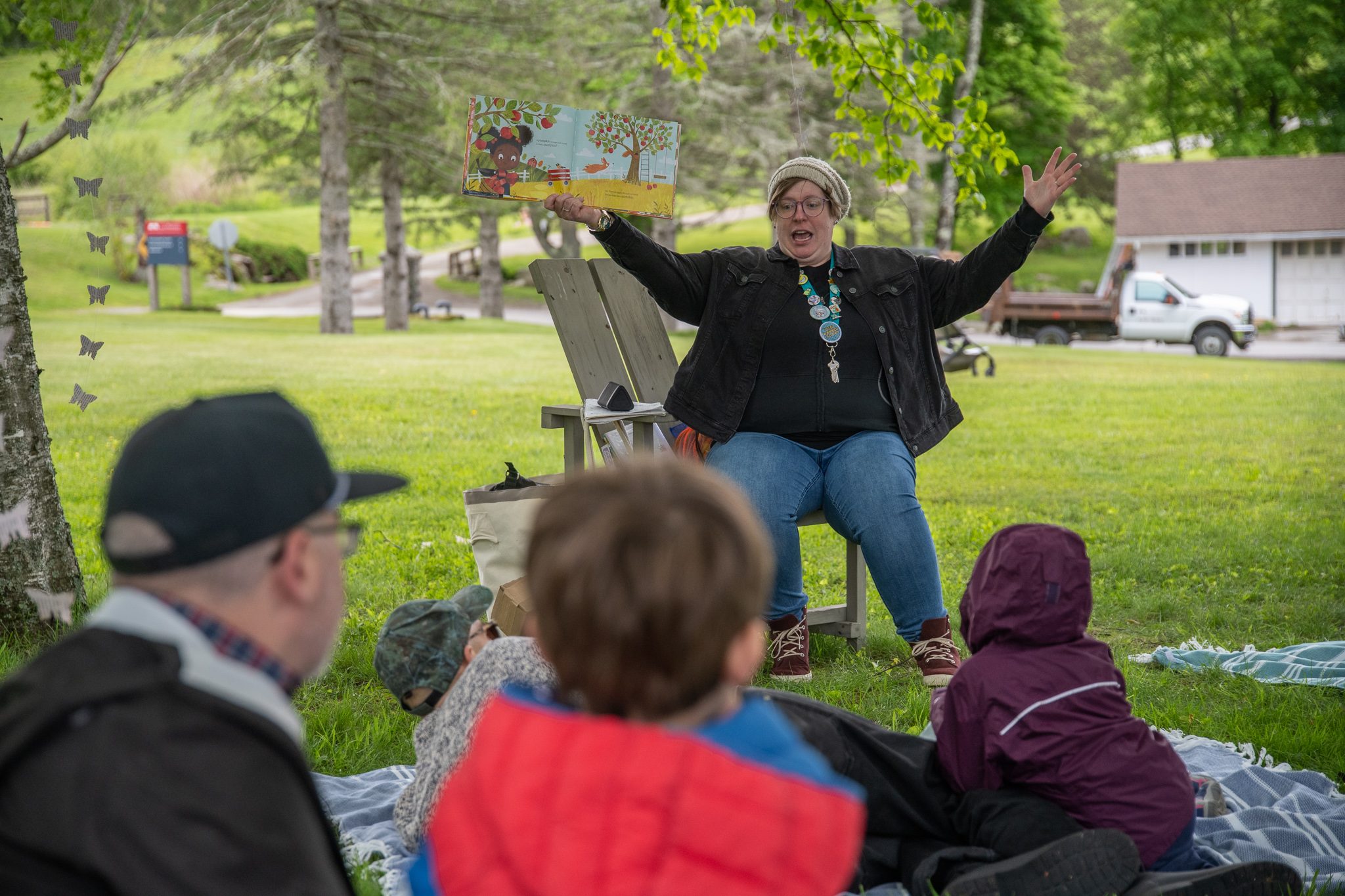 Arms flung wide, the storyteller reaches the best part, and the kids on the blankets are right there with her.