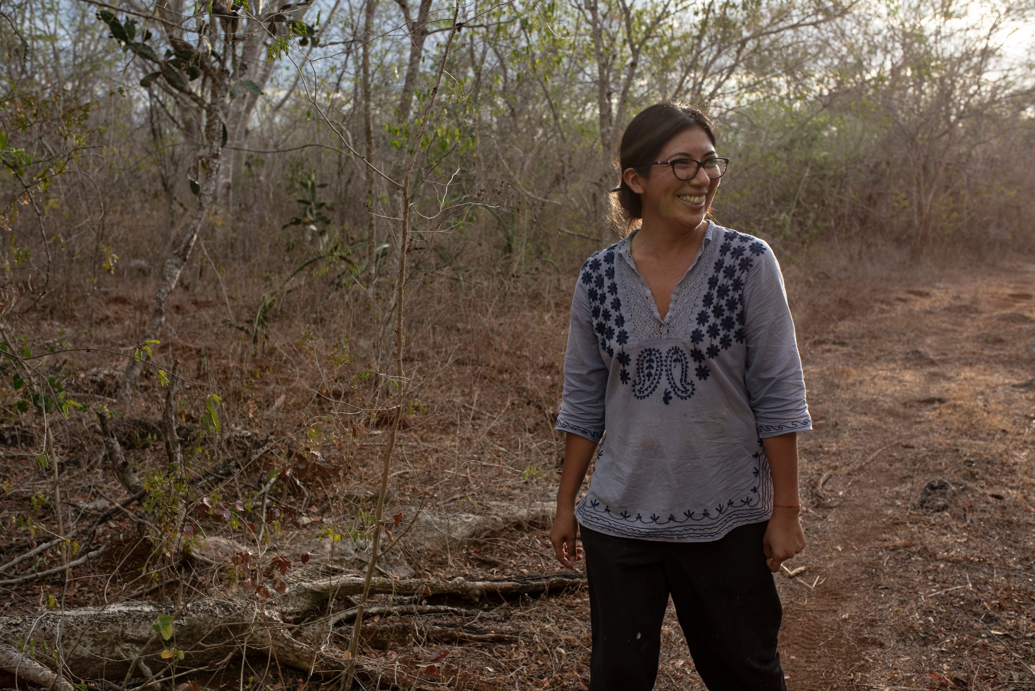 She stands smiling in the dry scrub as the light fades.