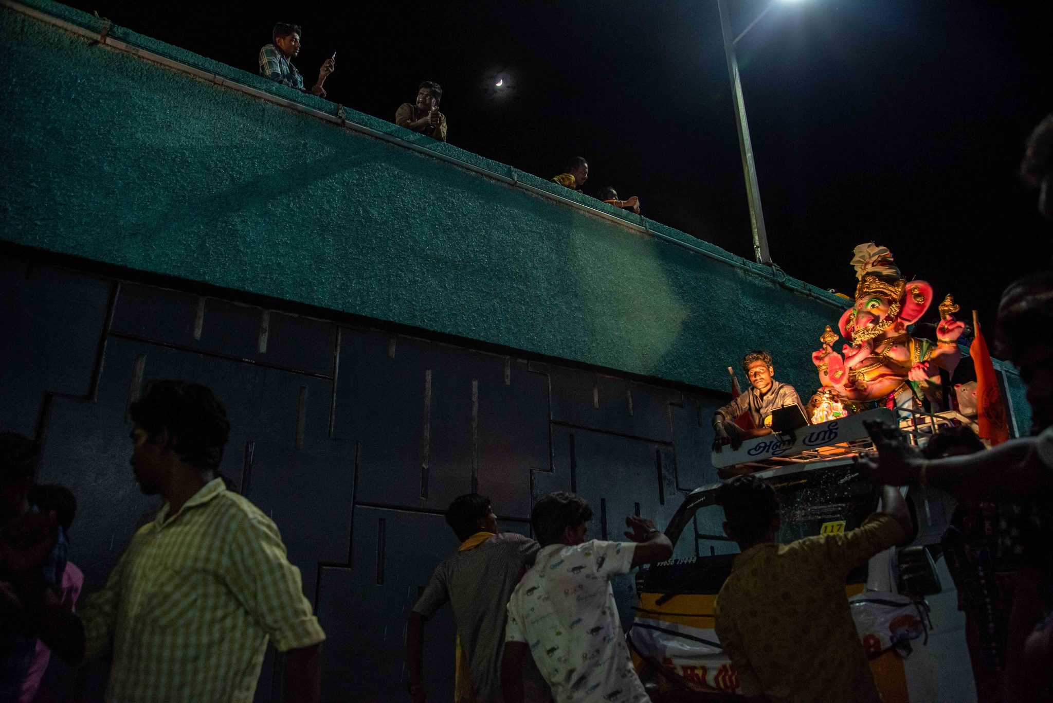 Faces turn toward the glowing idol as the procession moves along the wall.
