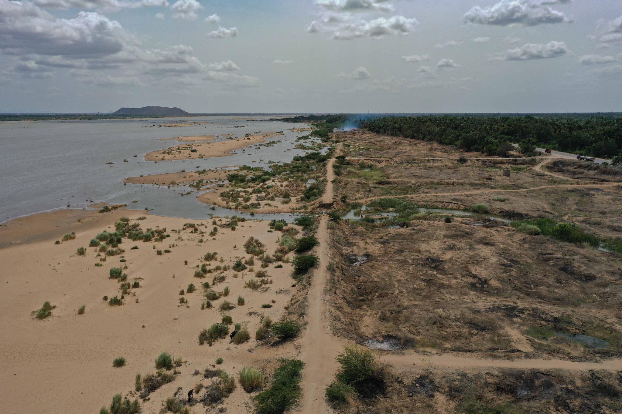 The river runs thin between wide banks of sand and scrub.