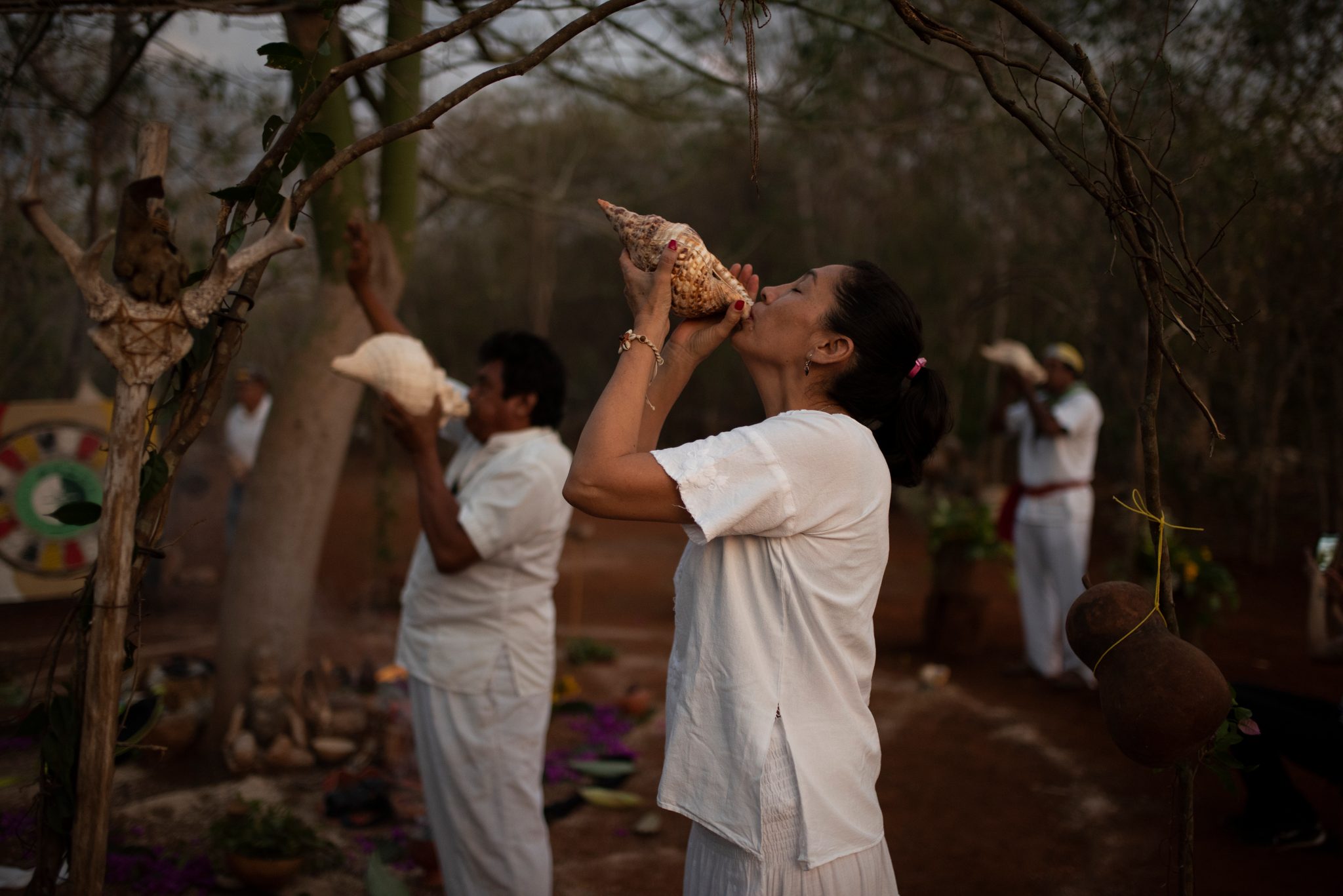 Two conch shells sound at once in the red dusk of the forest.