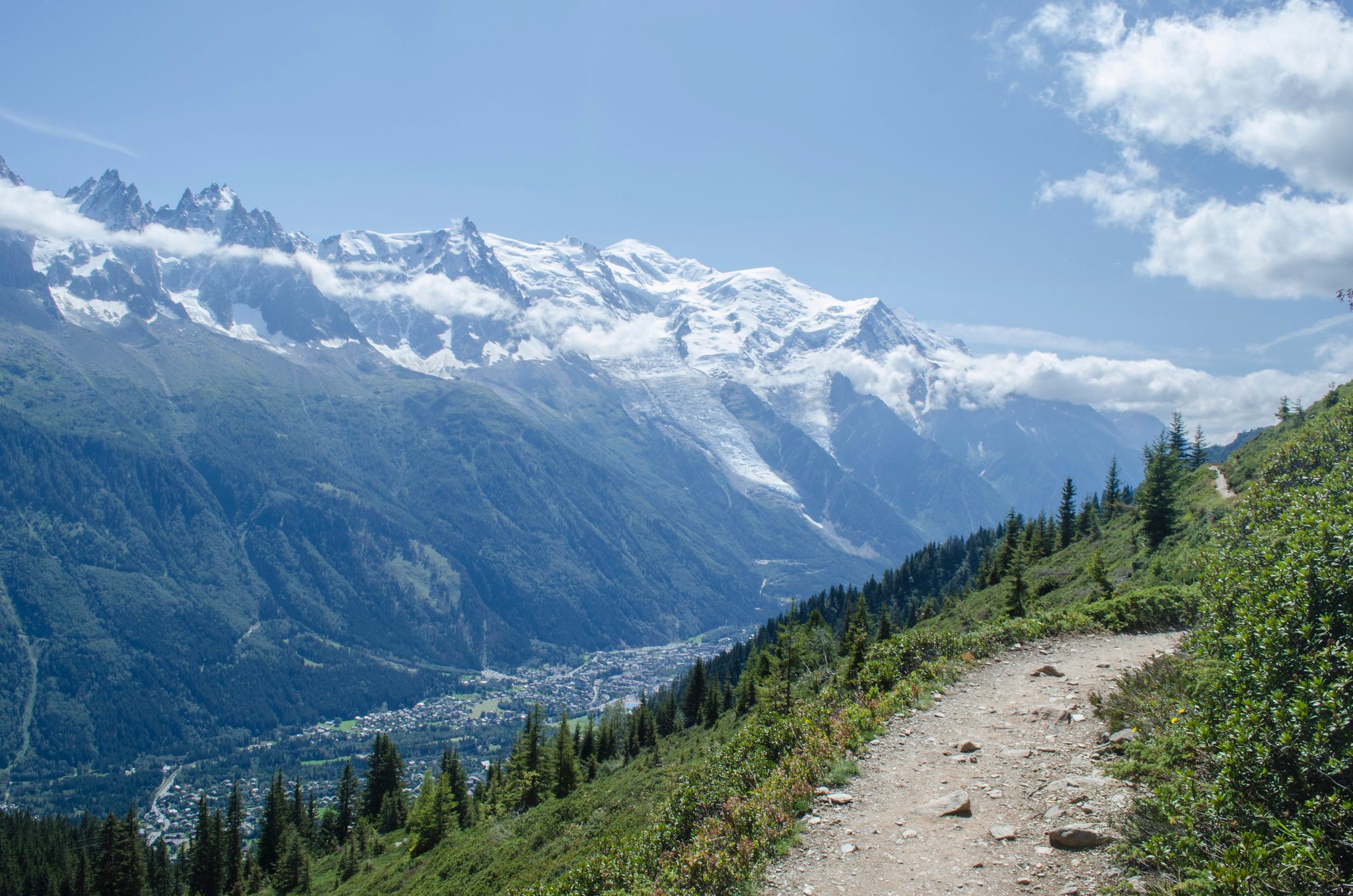 The trail bends high above the Chamonix valley, the glaciers of the Mont Blanc massif spilling down across the way.